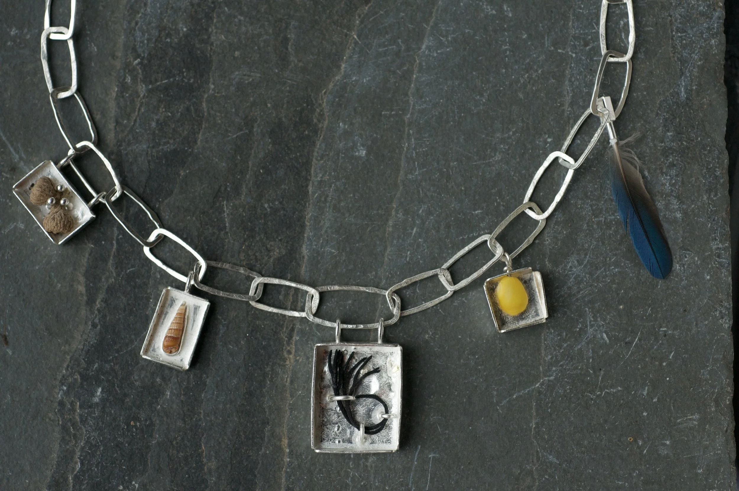 Collectors necklace with box charms and feather.jpeg