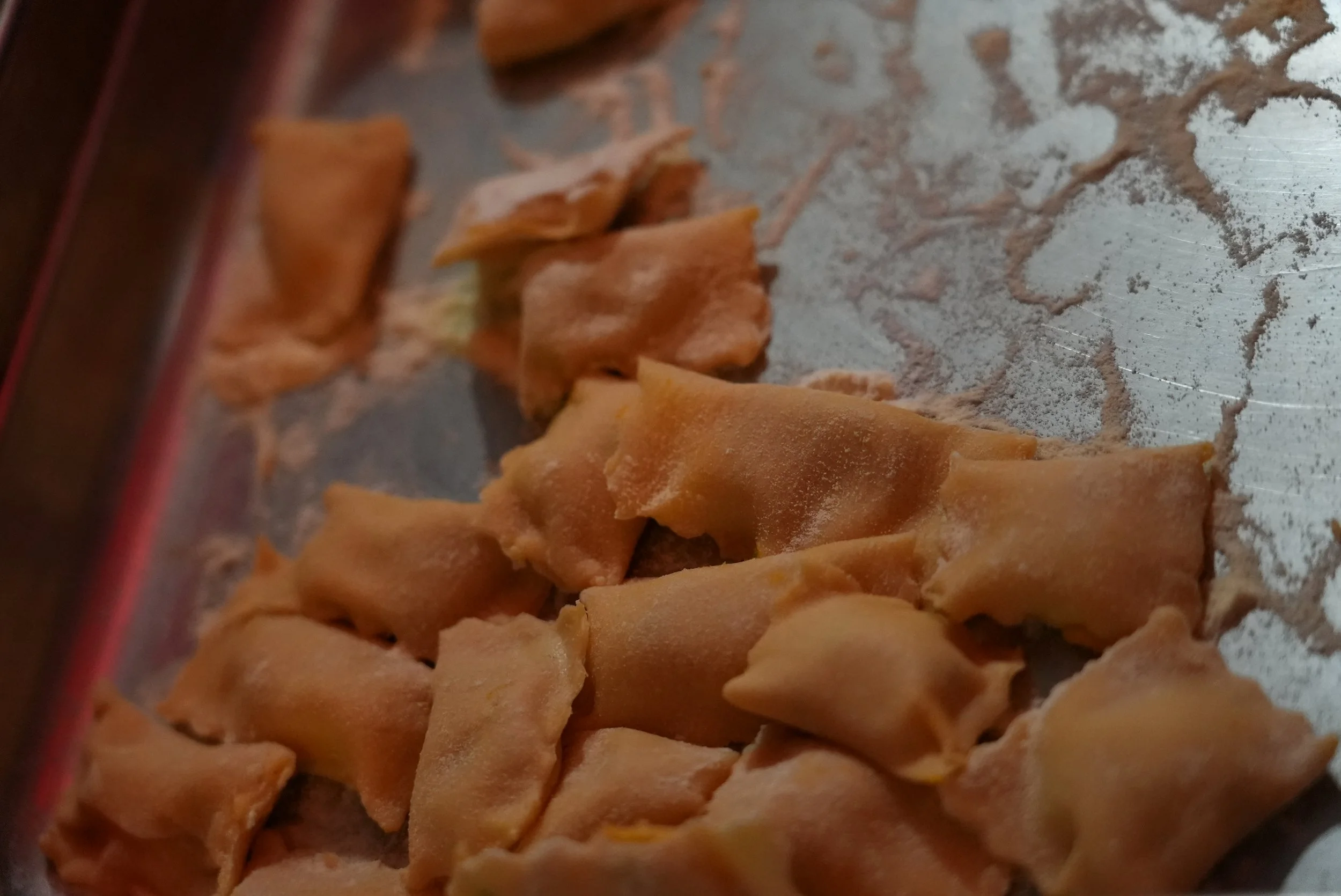 Uncooked tortellini pasta on a floured surface.