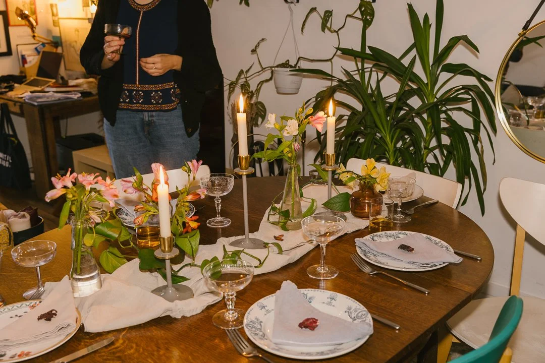Colorful dining table set with plates, napkins, silverware, glasses, and tall candles.