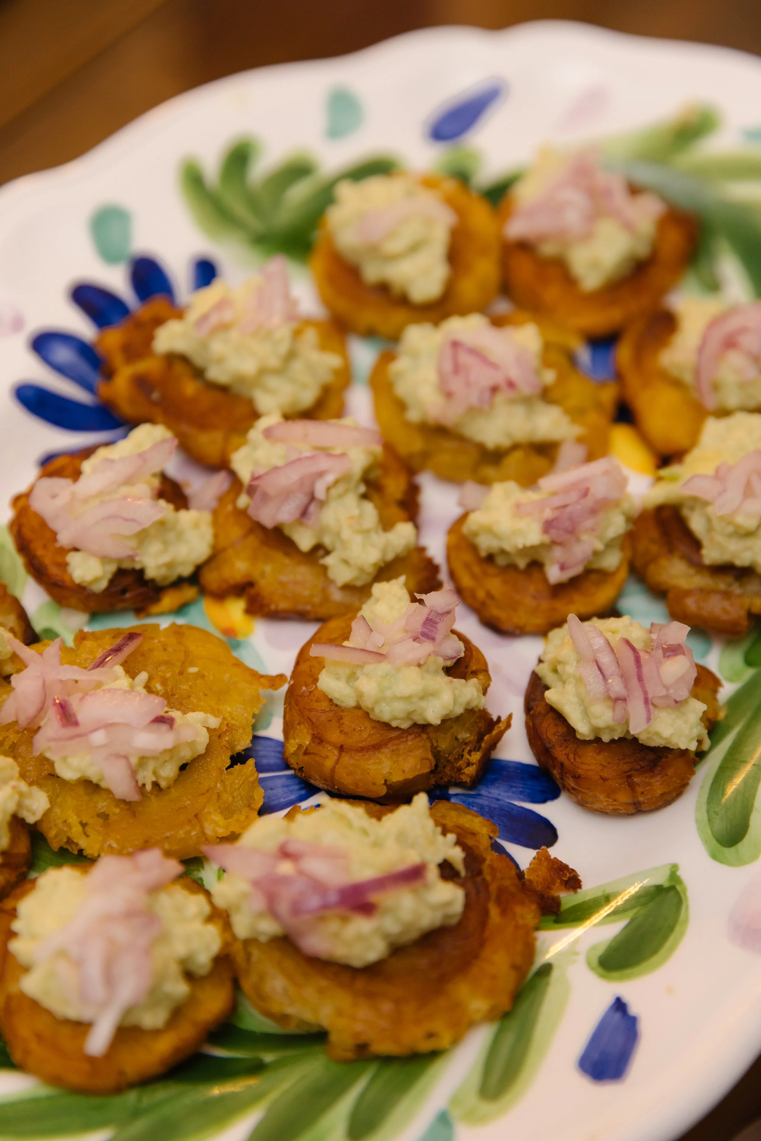 Fried okra topped with mashed potatoes and chopped red onions on a decorative plate.