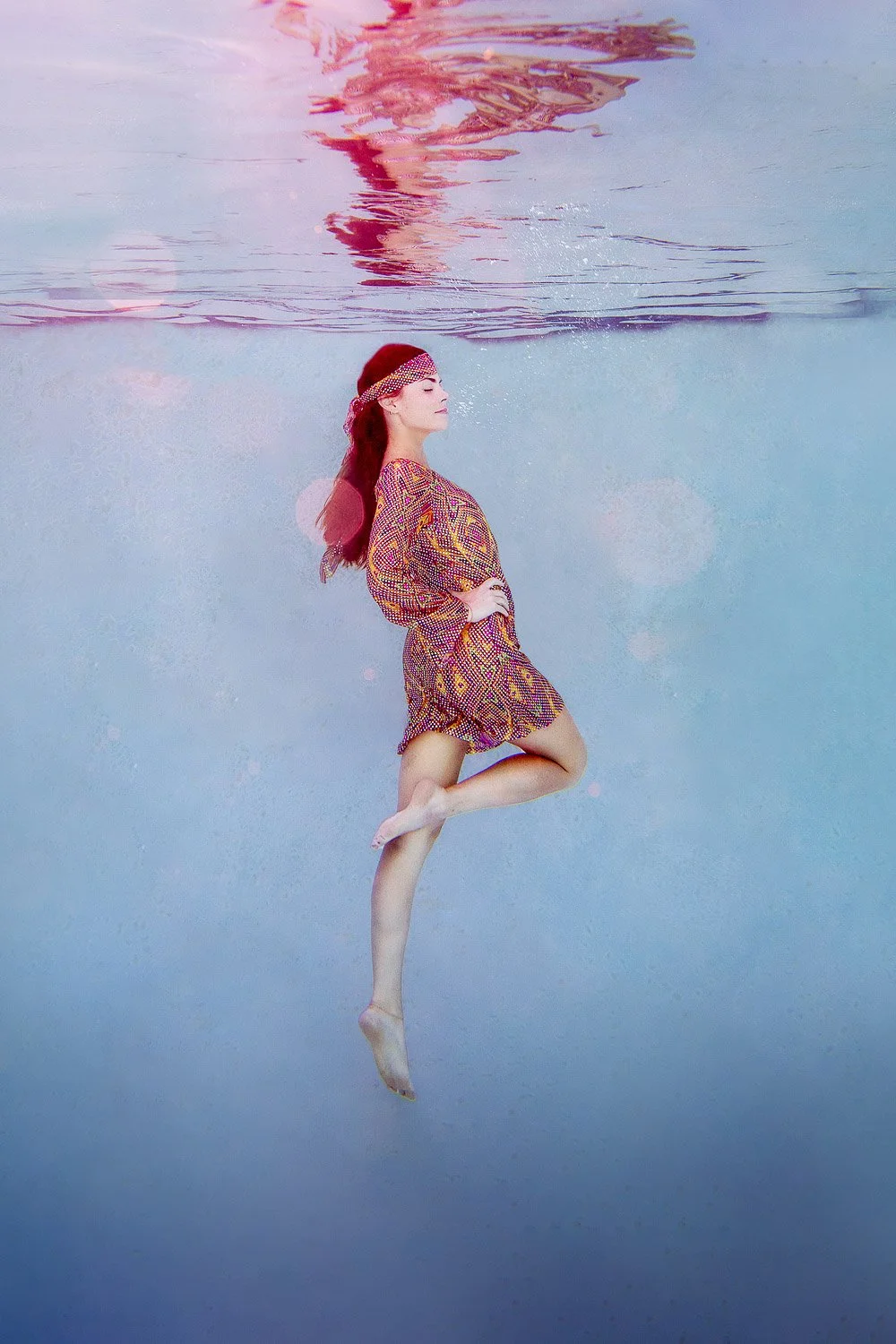 70s-inspired underwater portrait of a strong woman standing beneath the surface of a pool, hippie aesthetic, fine art photography