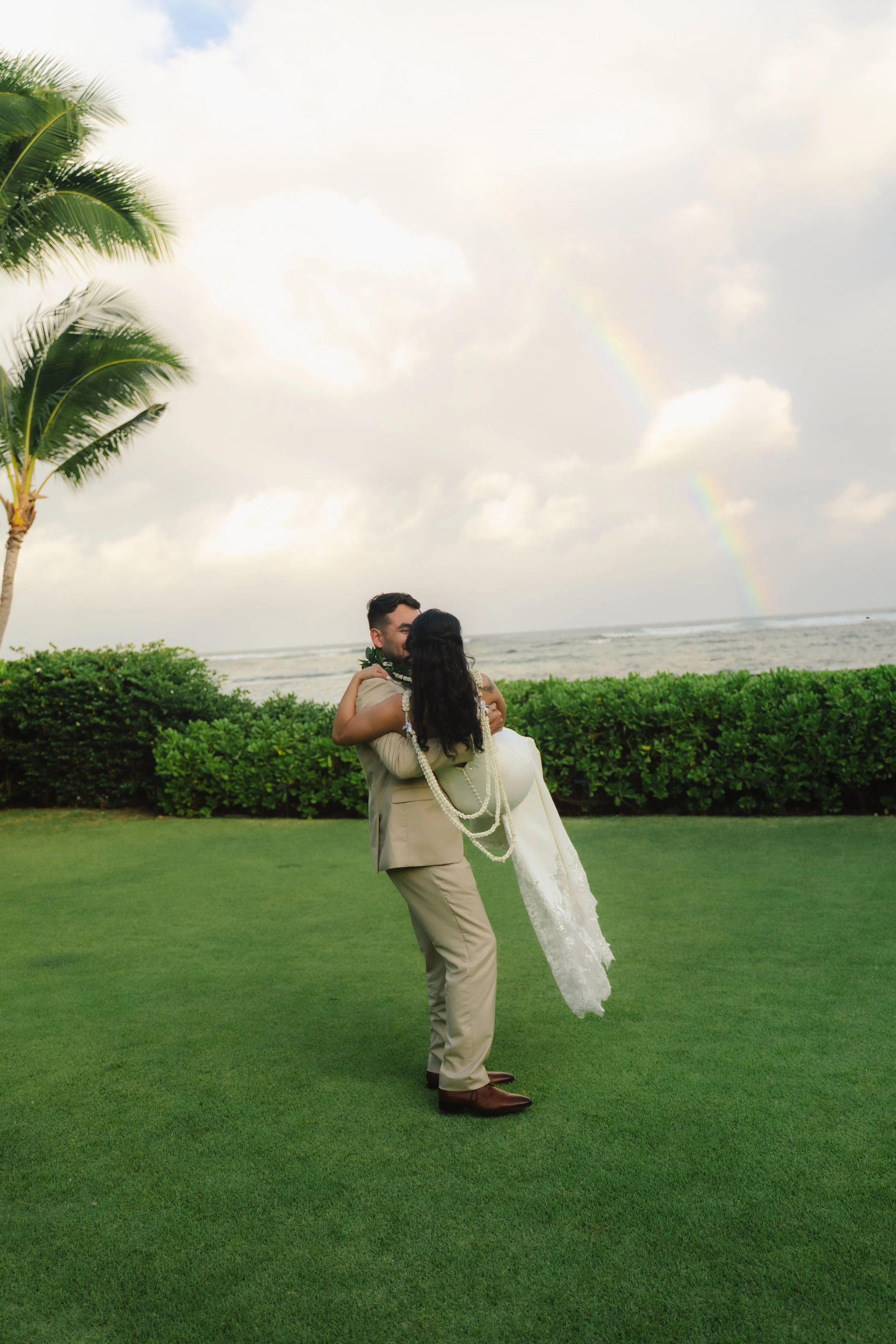 Bride and groom photographed beneath a rainbow at Kaimea Estates on Oahu