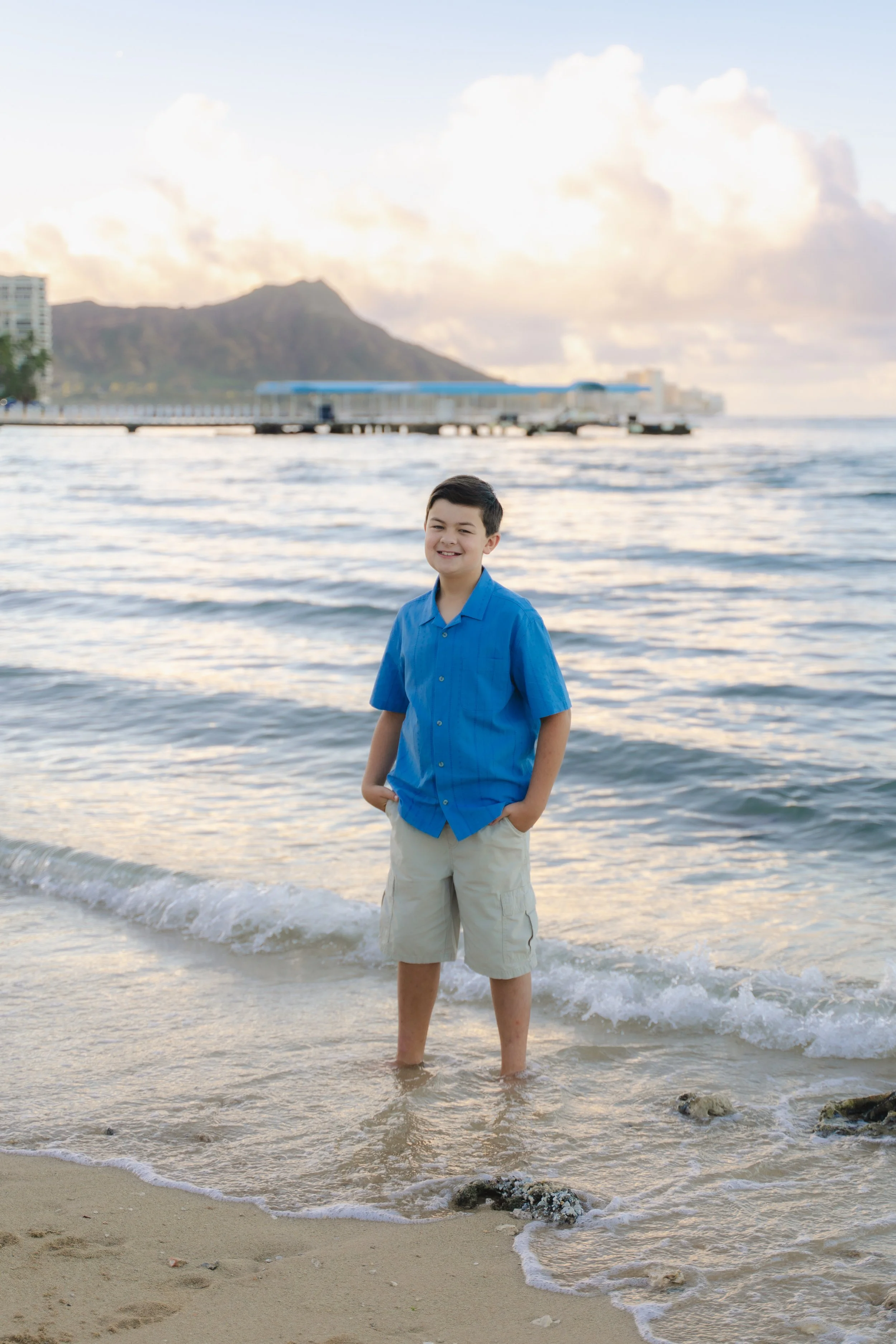 Candid family moments captured during a sunrise photoshoot at Hilton Lagoon on Oahu with warm golden light.