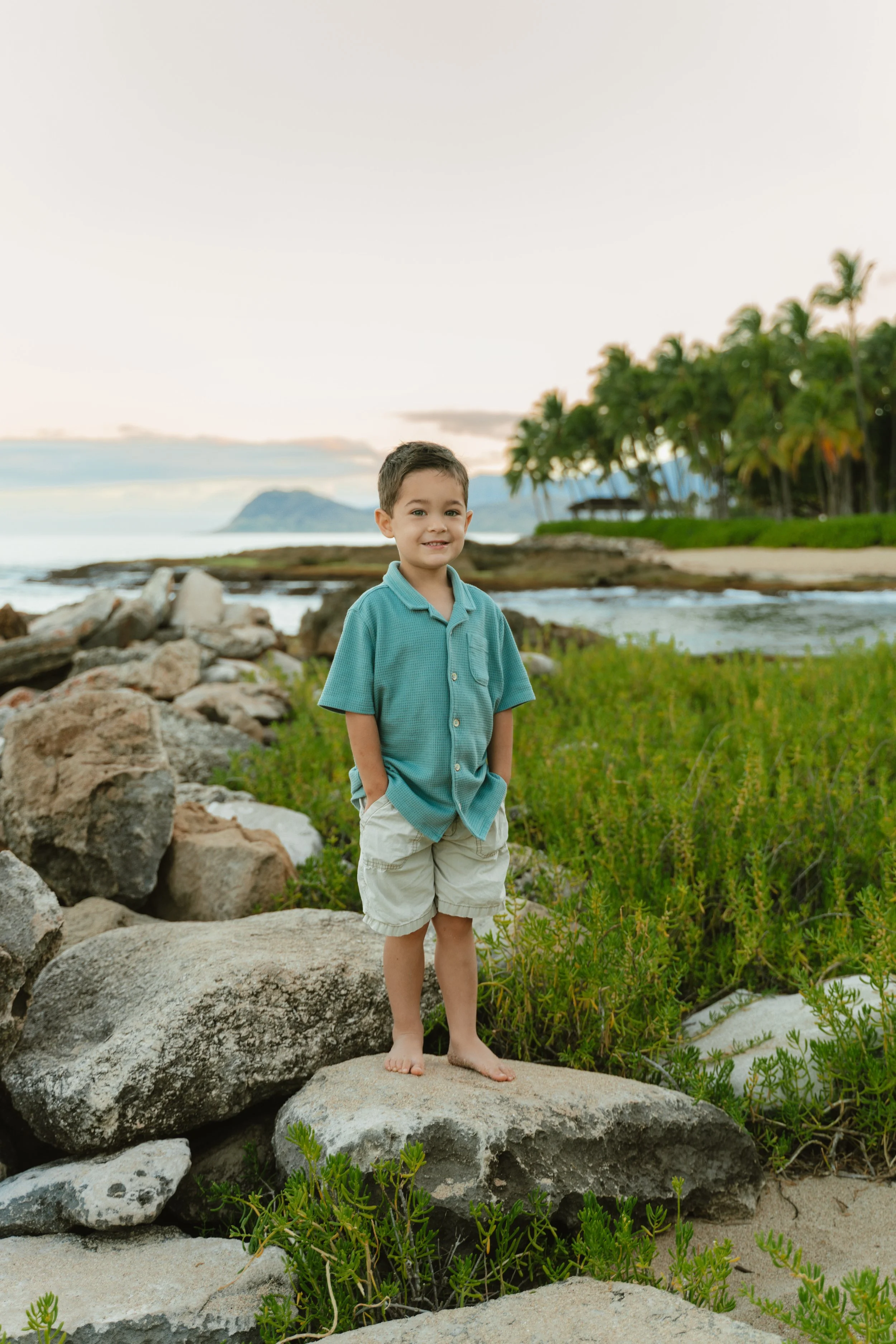 Family portrait session at Secret Beach during sunrise on Oahu featuring golden light and tropical Hawaii scenery.