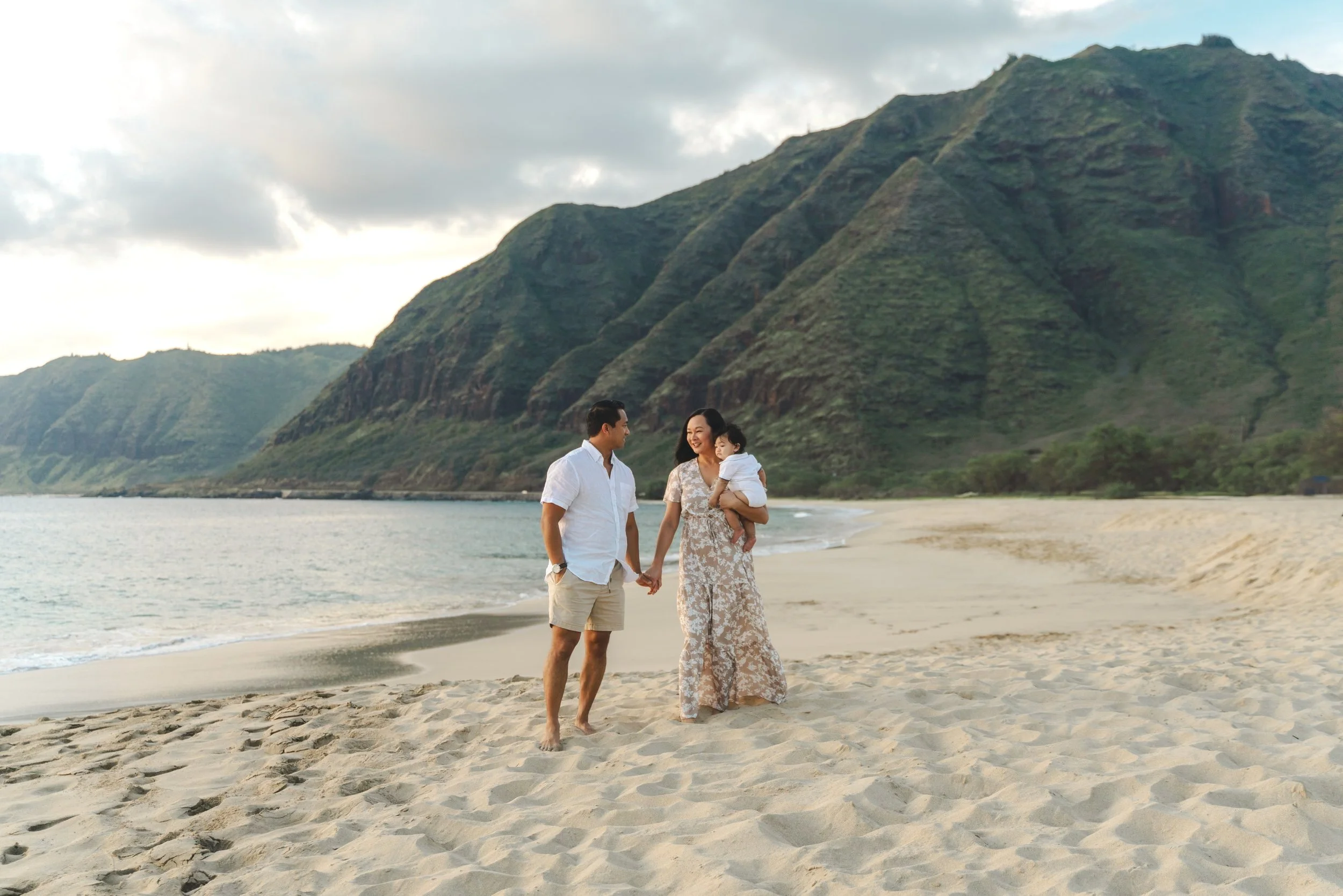 Family enjoying a sunset beach session with mountain views during an Oahu family photography shoot at Makua Beach.