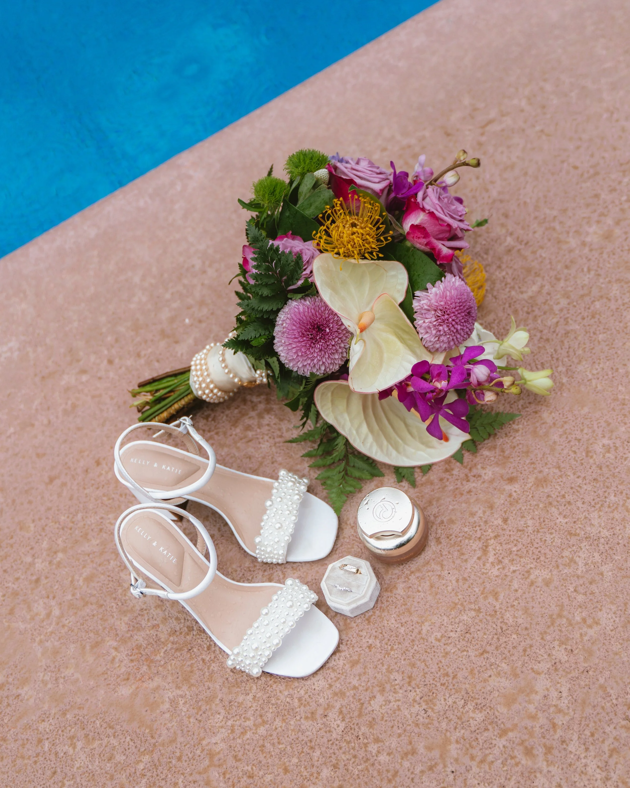 Wedding flowers and bridal shoes photographed beside the pool at Kaimea Estates on Oahu