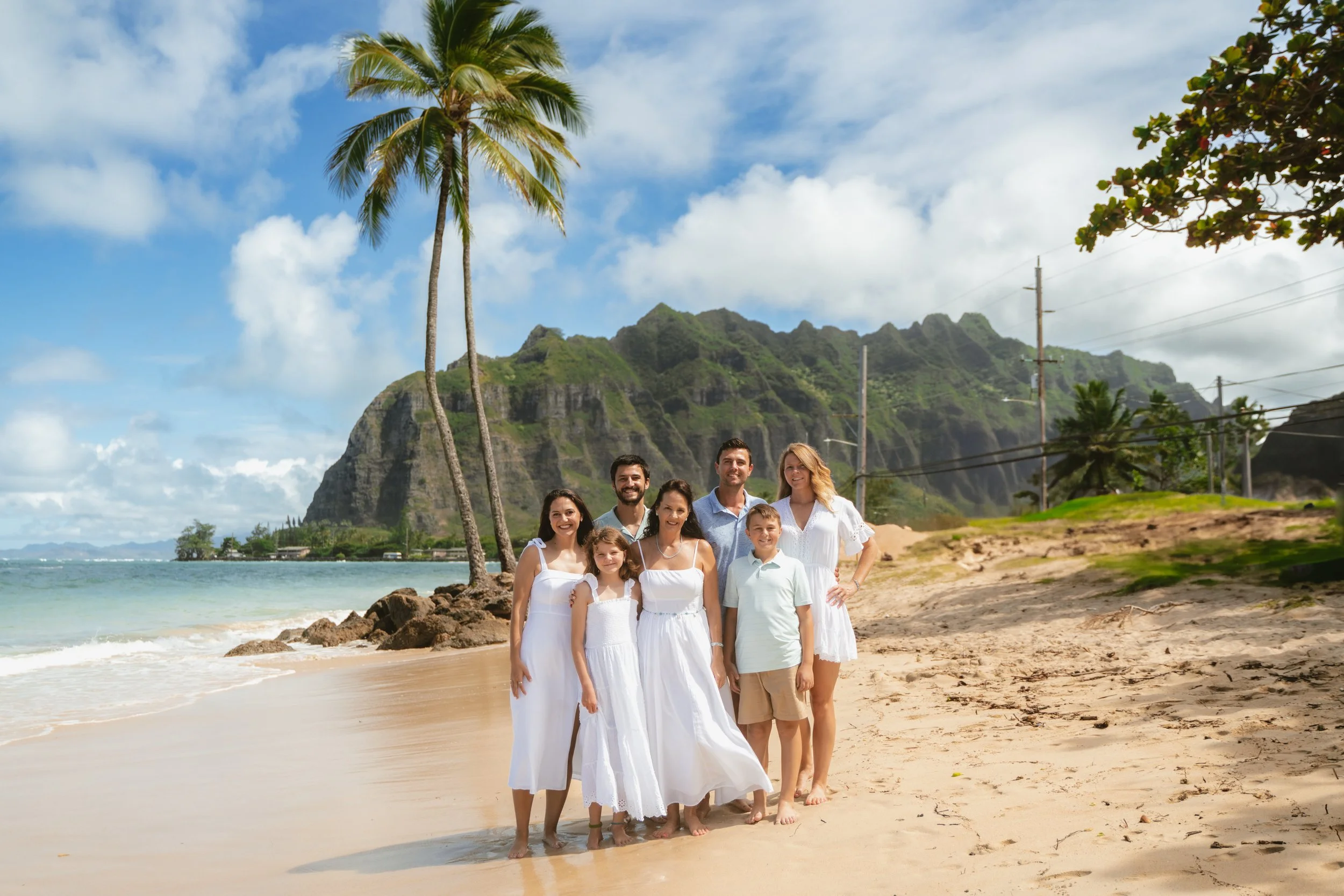 Family enjoying time together on the beach with mountain views during an Oahu family photography session in Kaaawa.