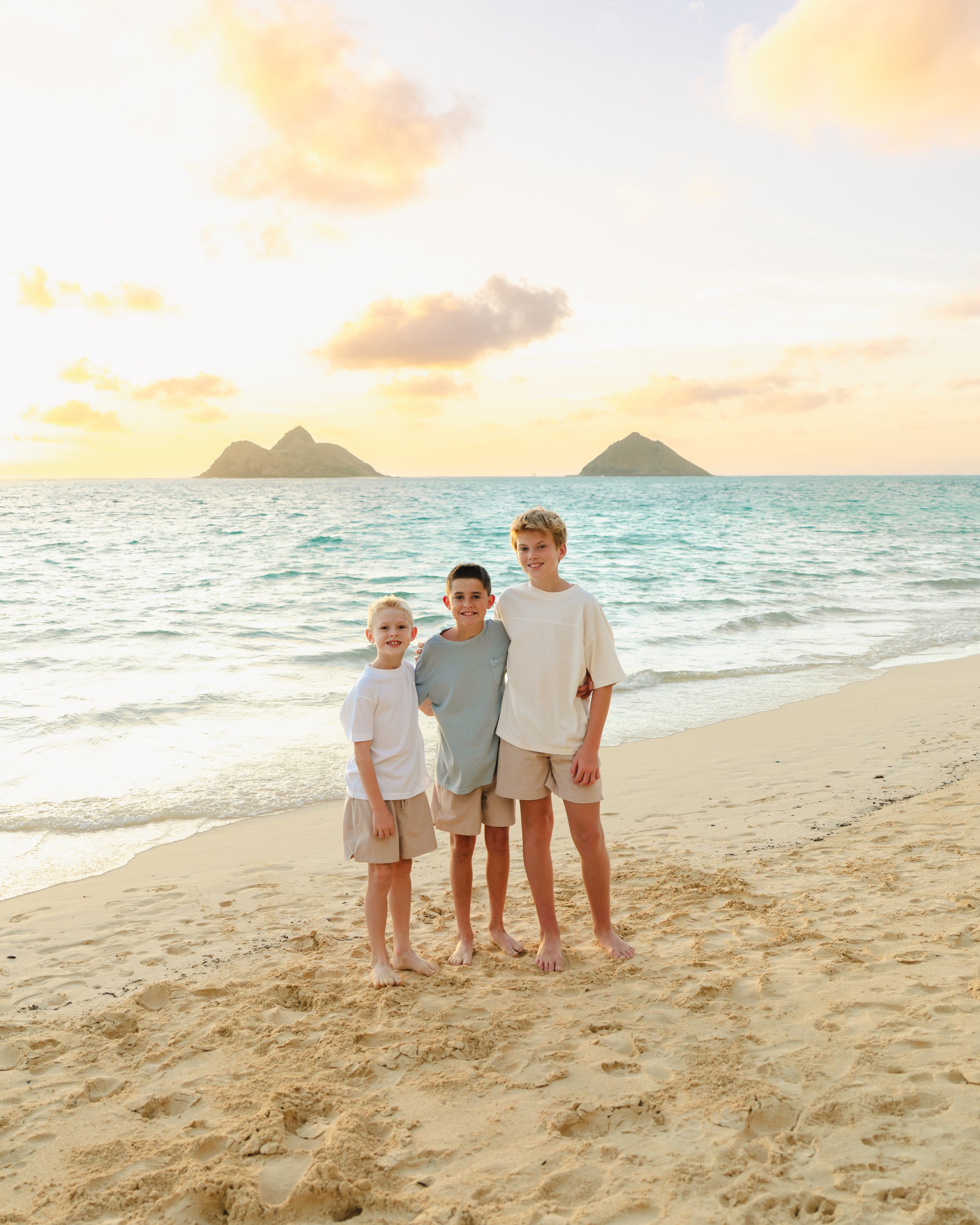 Three brothers together being photographed at sunrise at Lanikai Beach, Oahu Hawaii
