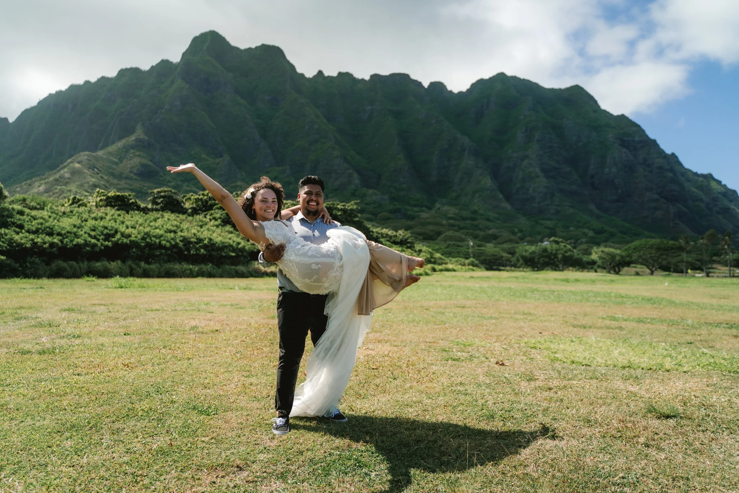 Couple celebrating their wedding with mountain and ocean views during an Oahu wedding photography session at Kualoa Regional Park.