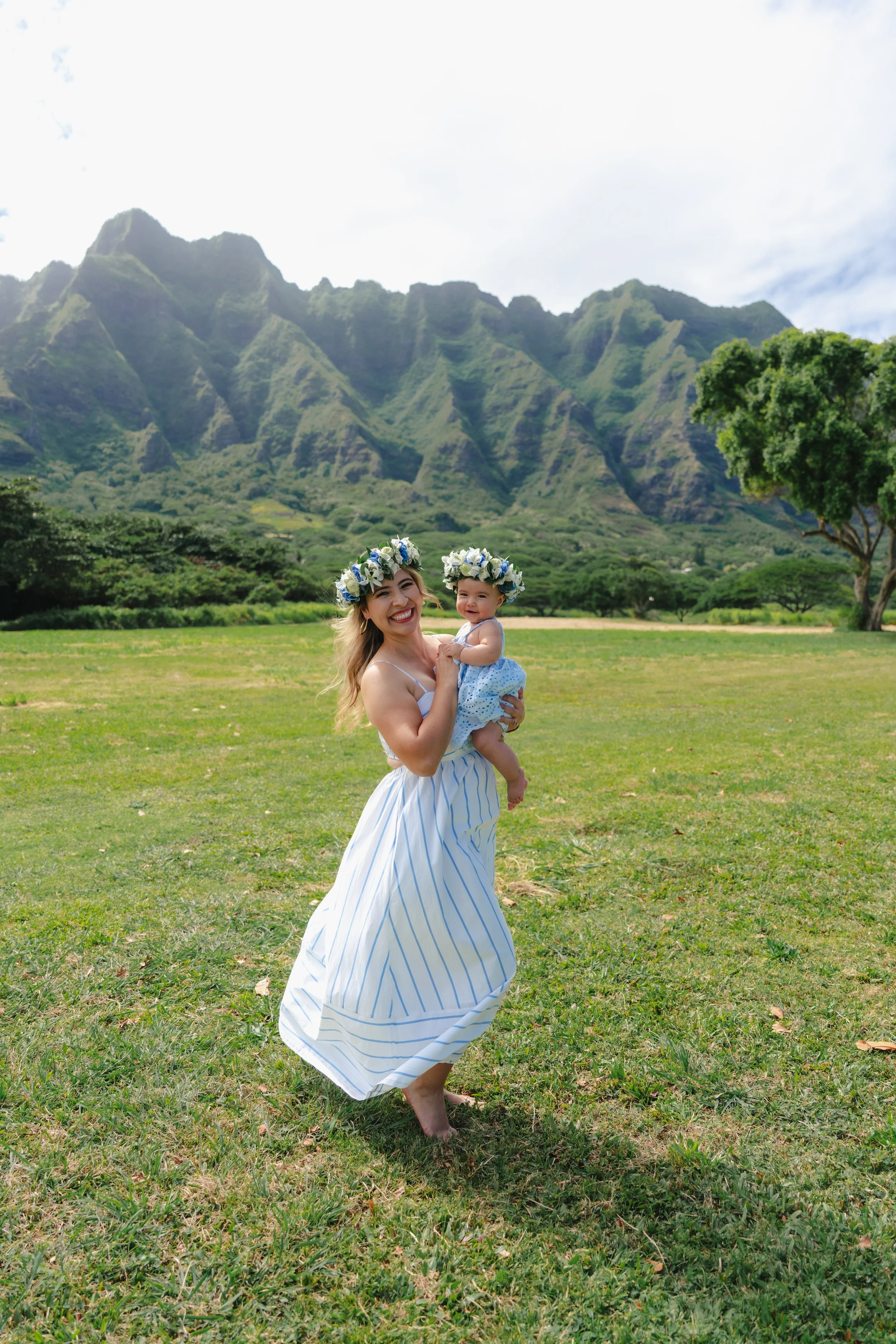 Mother and baby wearing a traditional flower lei poʻo during a family photoshoot at Kualoa Regional Park