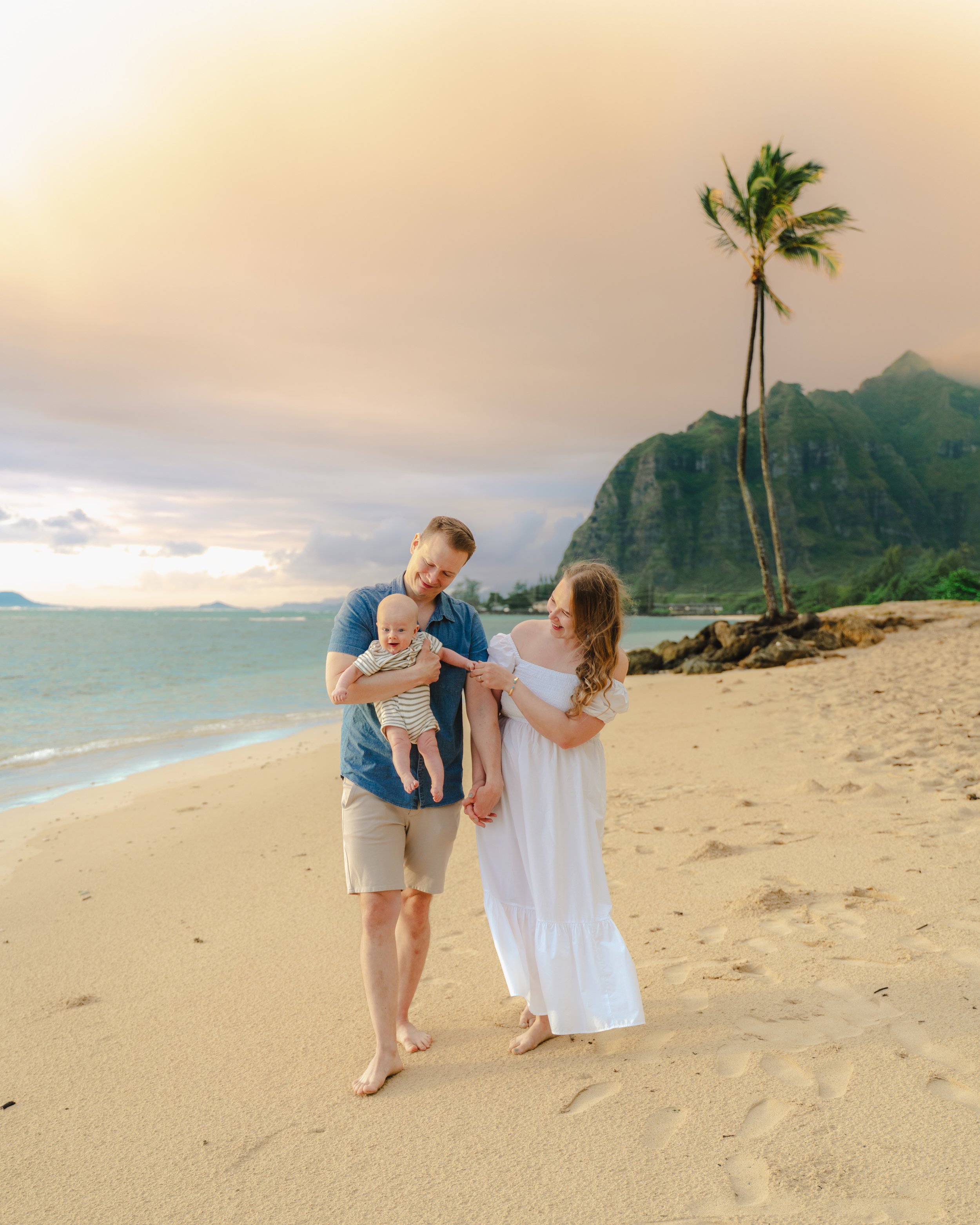 Sunrise newborn photography on Oahu with ocean and mountain backdrop.