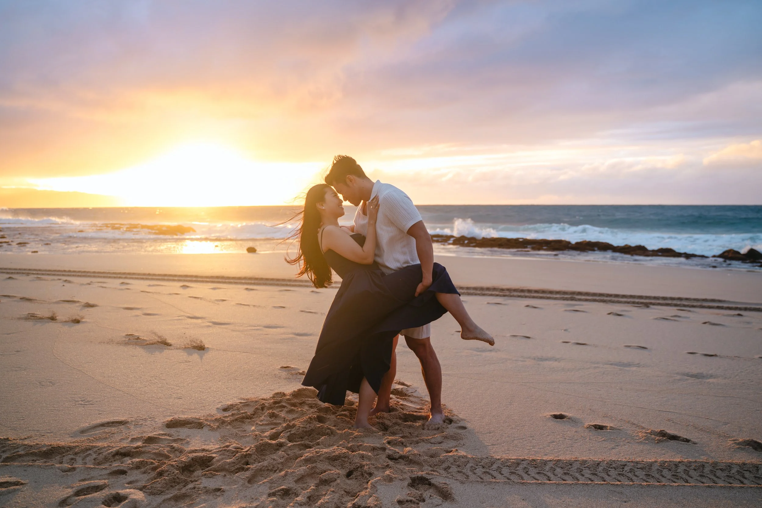Engaged couple celebrating by the shoreline during an Oahu engagement photography session at Keiki Beach on the North Shore.