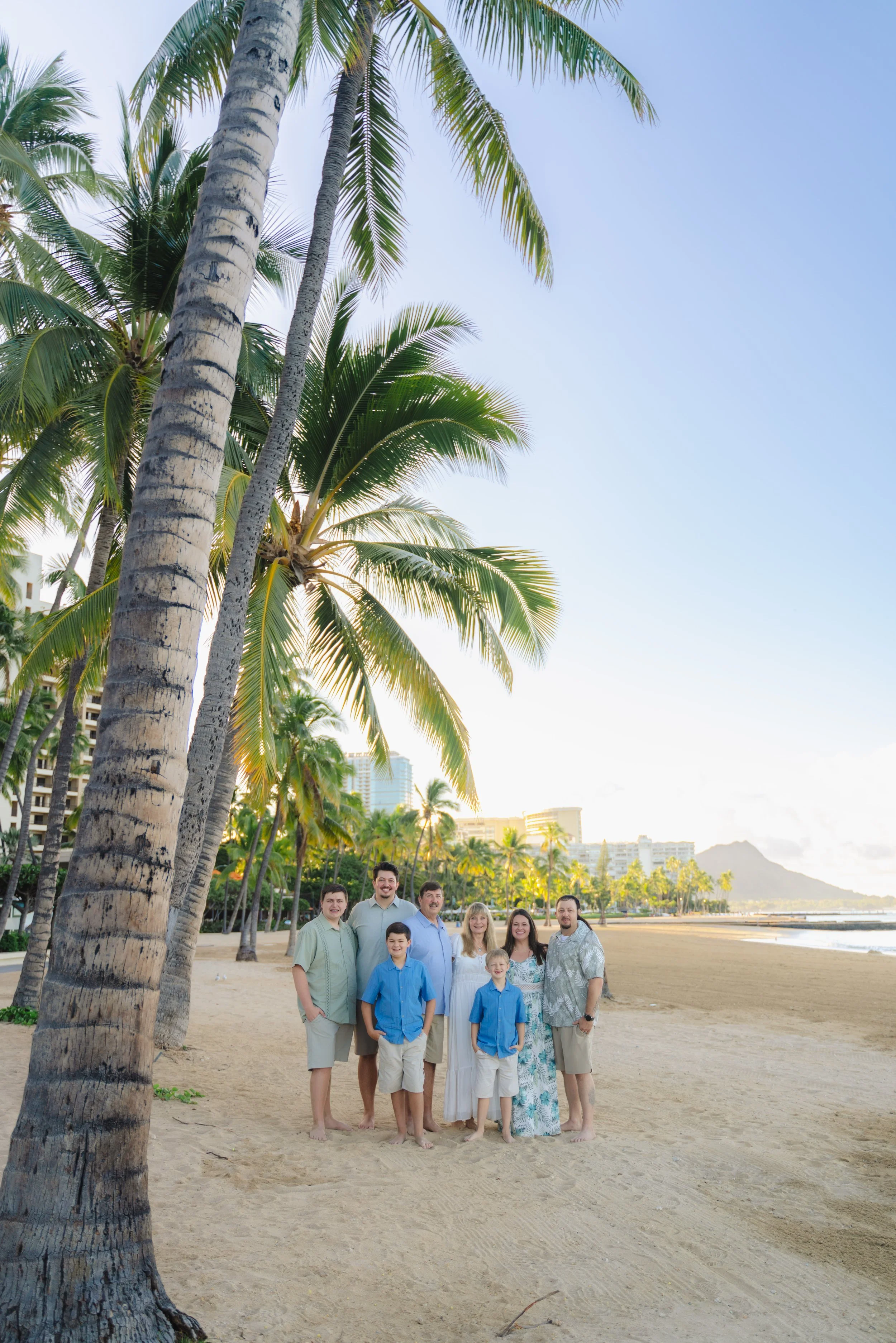 Family portrait session at Hilton Hawaiian Village Lagoon during sunrise featuring tropical scenery and beautiful Hawaii colors.