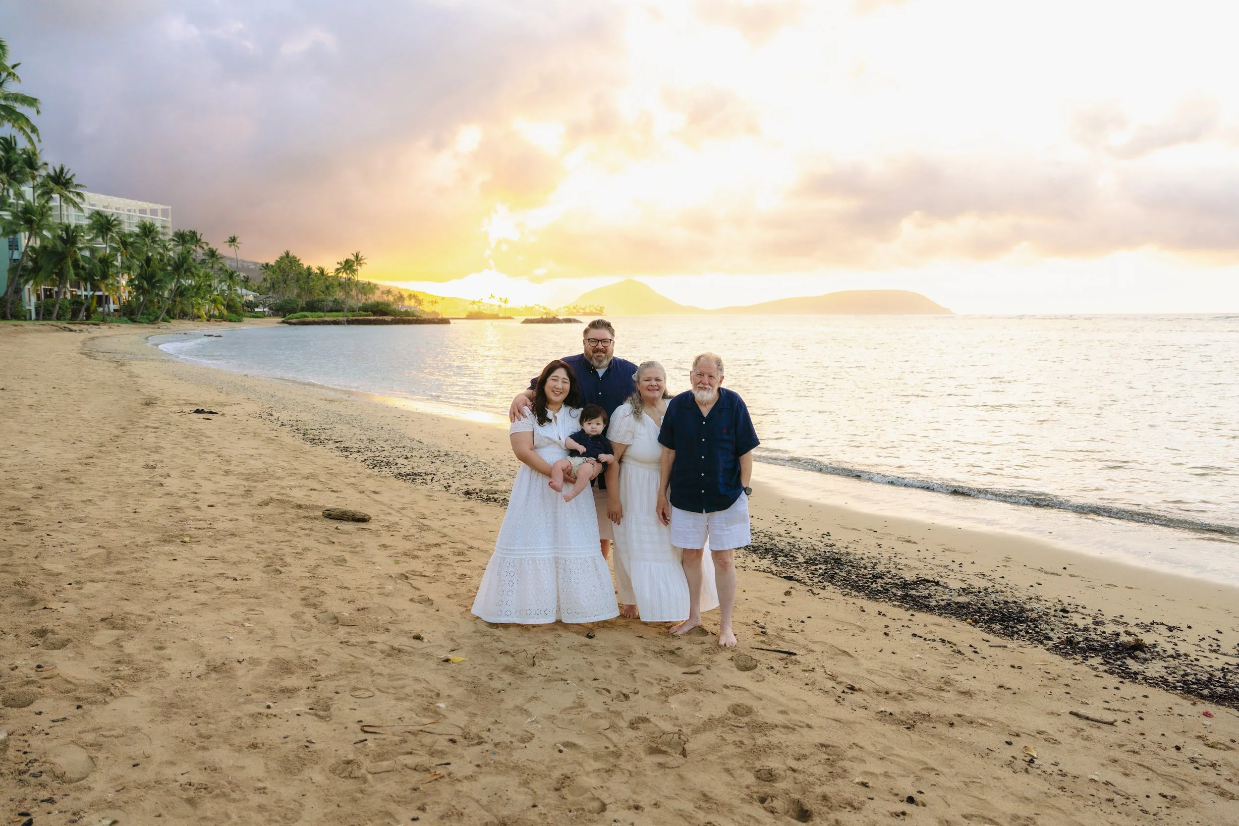 Family enjoying a sunrise beach photoshoot at Kahala Beach on Oahu