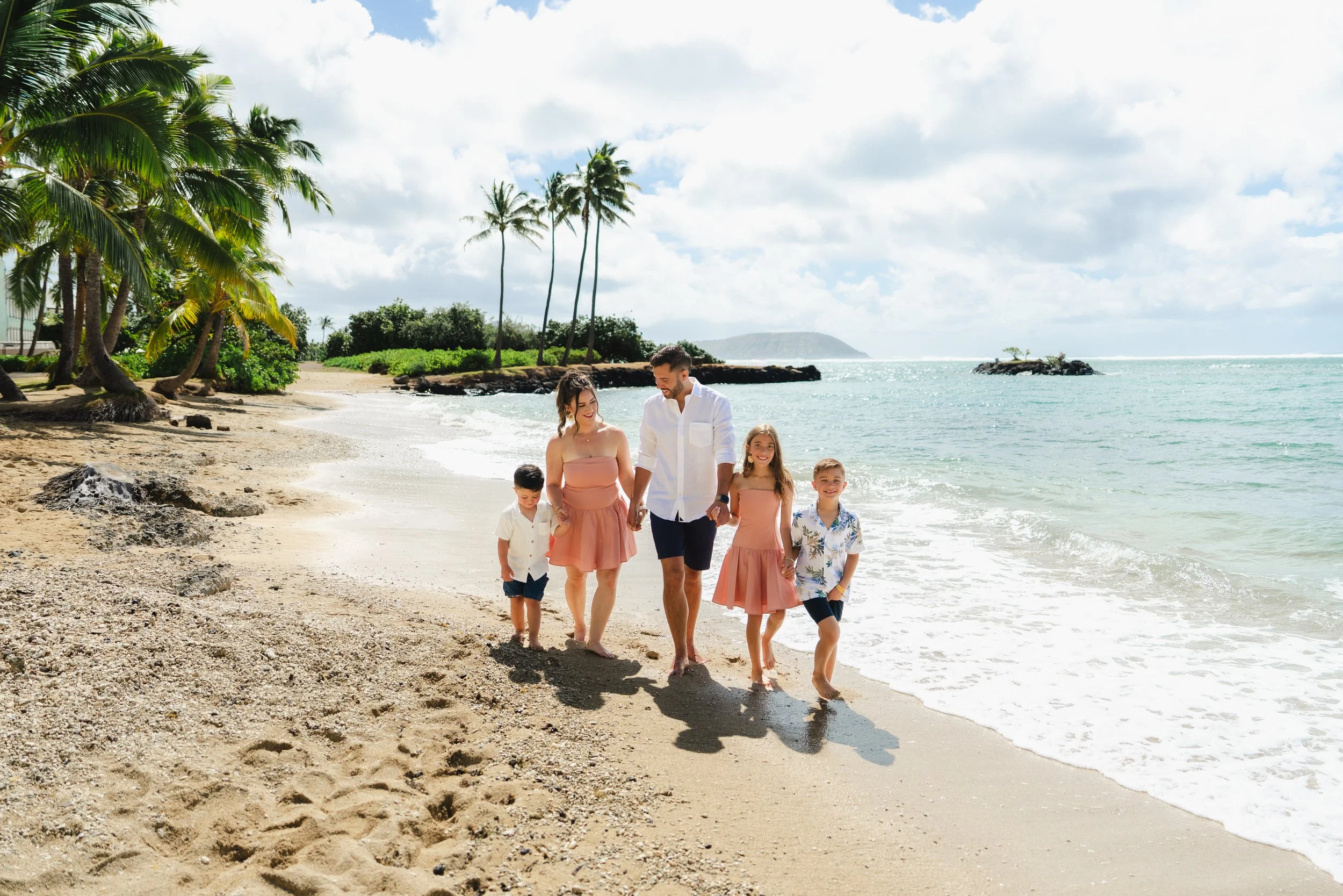 Oahu family walking along the beach surrounded by tropical scenery at Kahala Beach