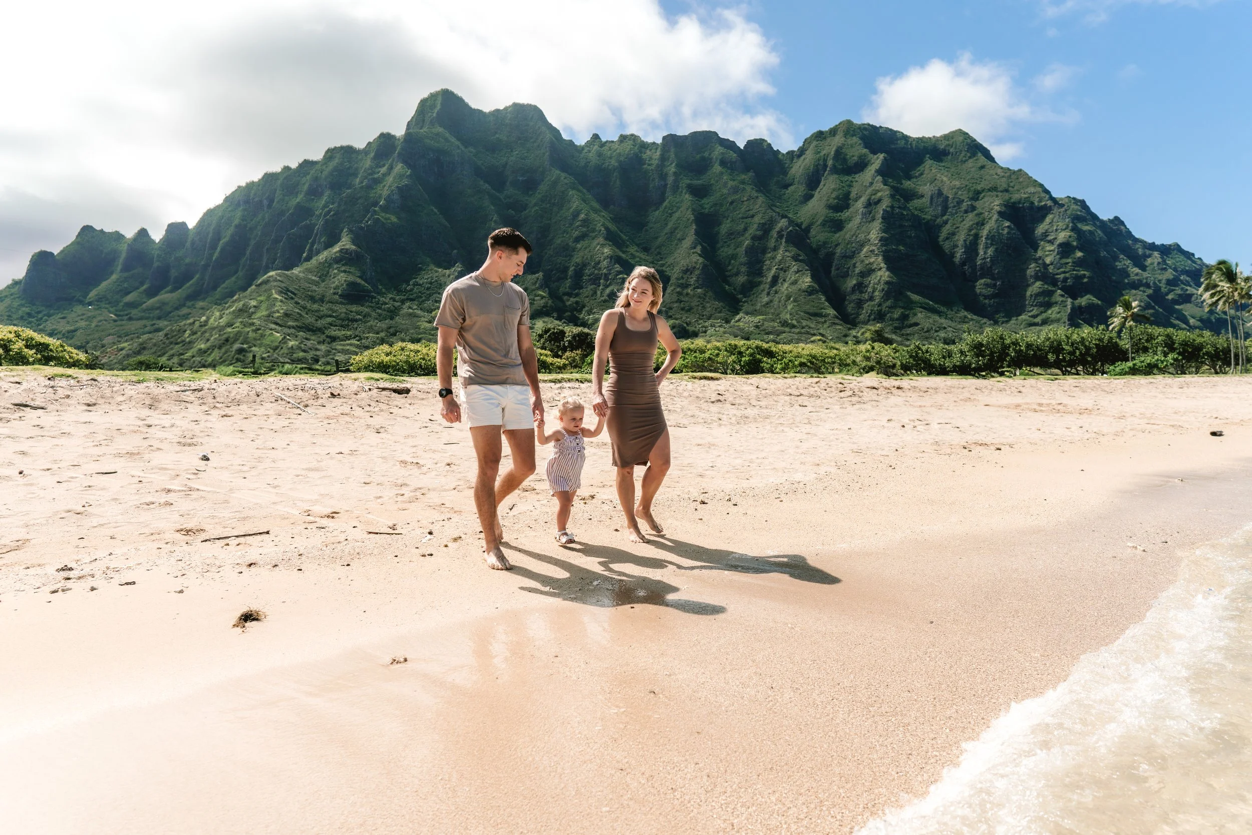 Family enjoying time together on the beach during an Oahu family photography session at Kualoa Regional Park.