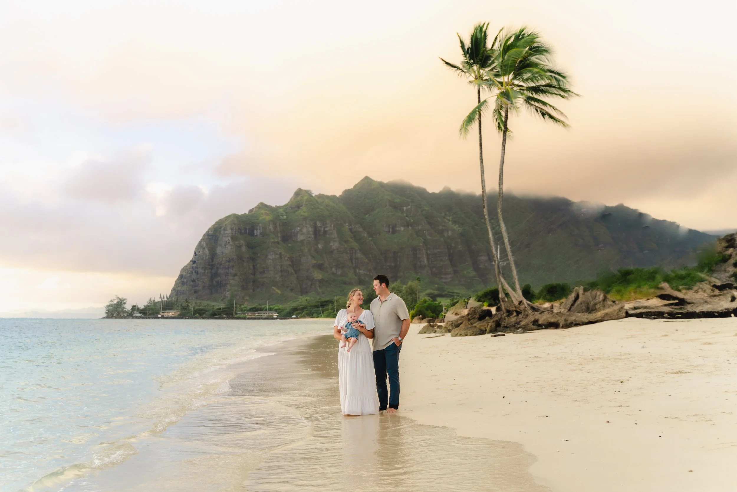 Family together on the beach with ocean views during family photos on Oahu in Kaaawa.