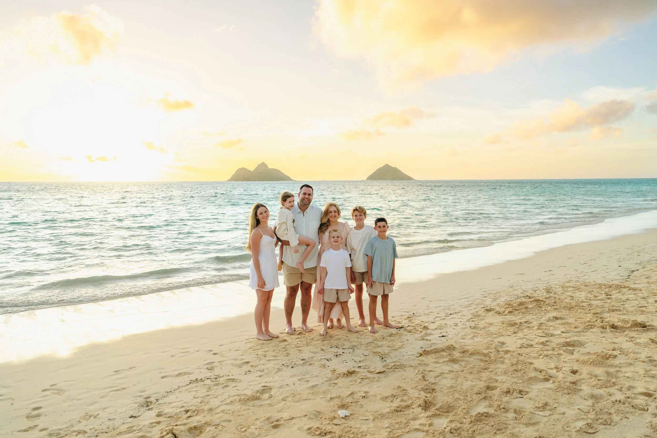 Family photographed at sunrise on the white sand and turquoise water of Lanikai Beach on Oahu