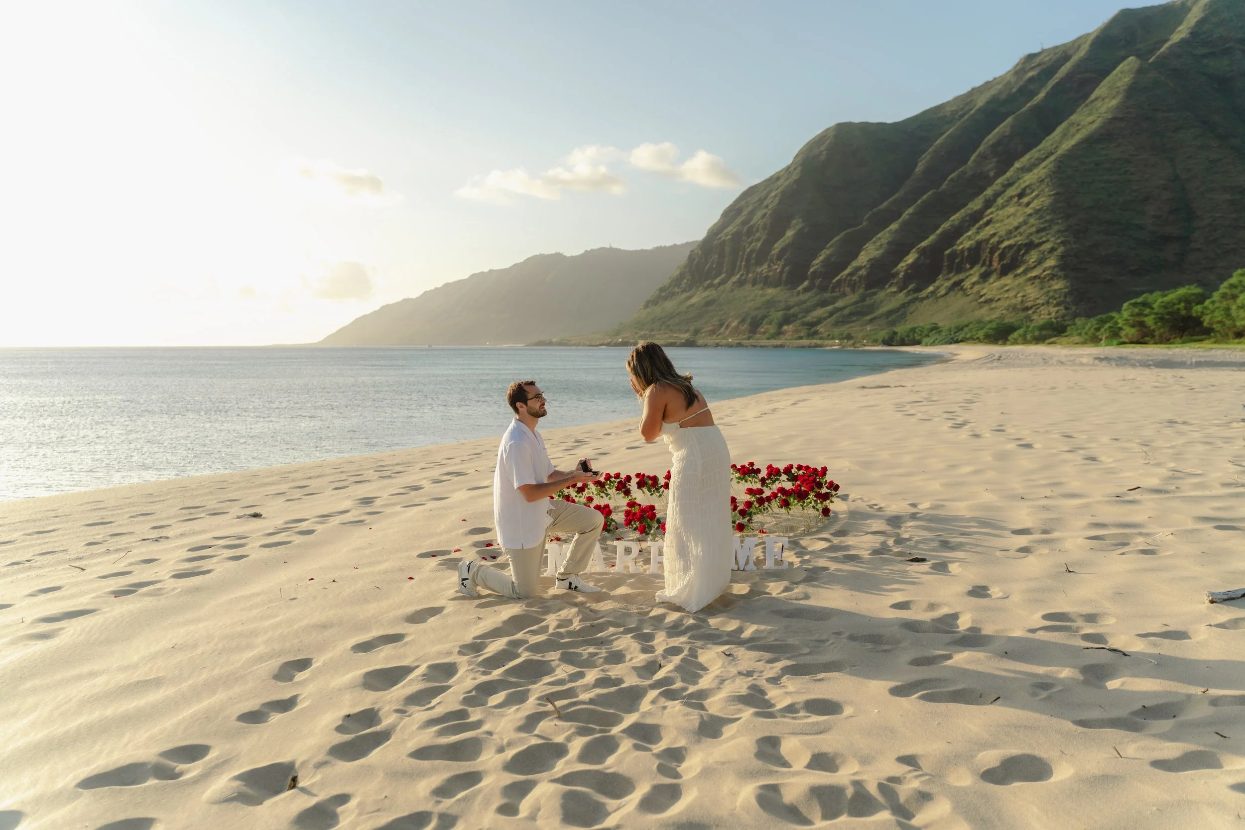 Couple celebrating a beach proposal at sunset during an Oahu proposal photography session at Makua Beach.