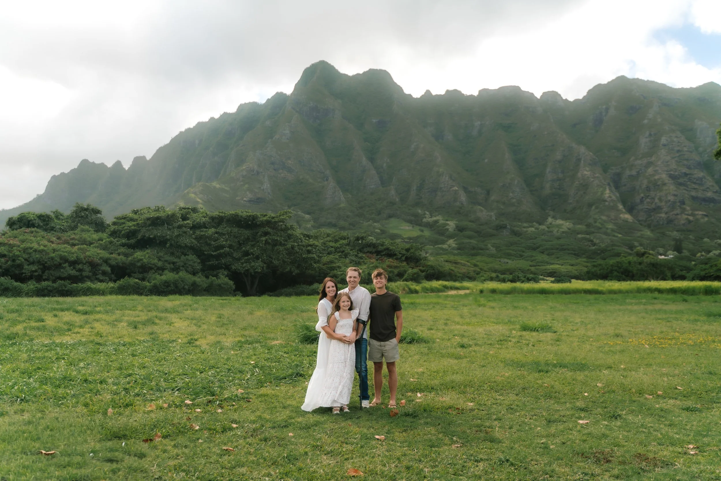 Family posing for vacation photos at scenic Kualoa Regional Park on the windward side of Oahu