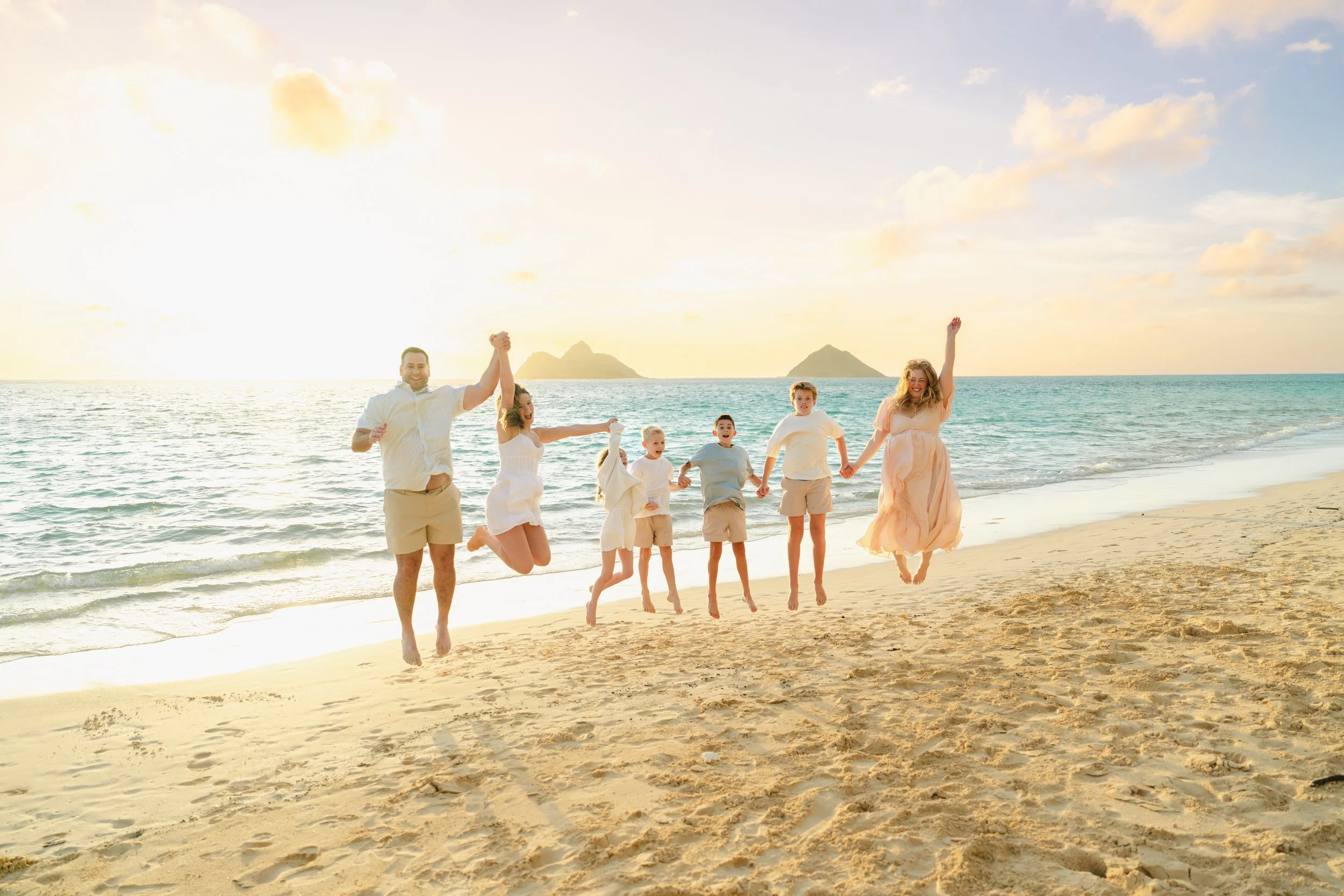 Family photographed at sunrise on the white sand and turquoise water of Lanikai Beach on Oahu