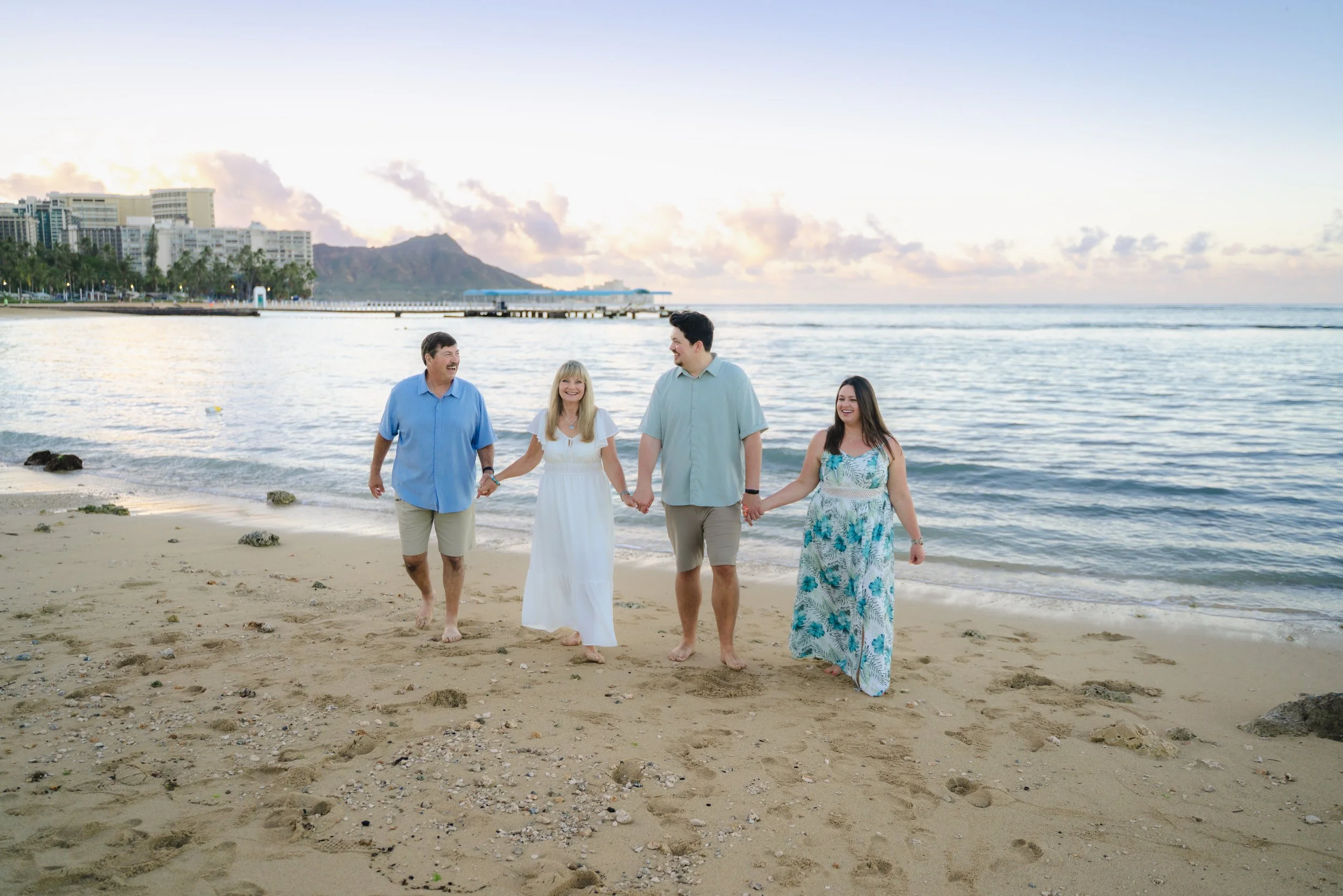 Parents and children walking together along Hilton Lagoon in Waikiki during a sunrise family photography session.