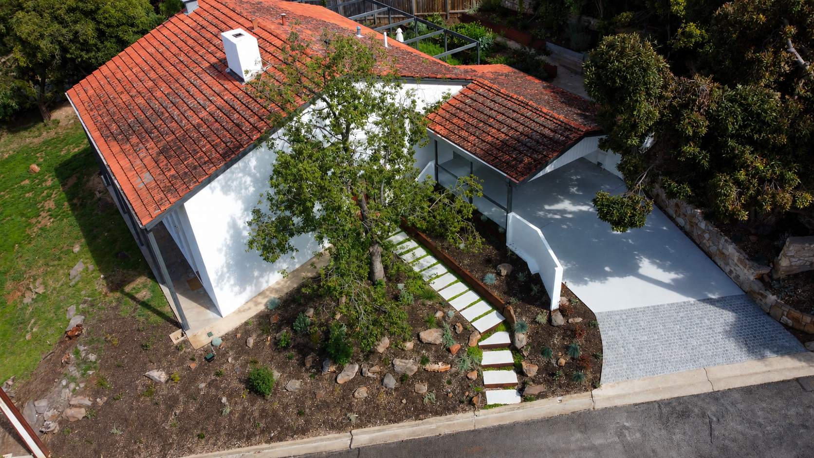 Aerial view of a modern driveway in Beaumont with Coren steel edging and retaining, grey cobbles and native planting.