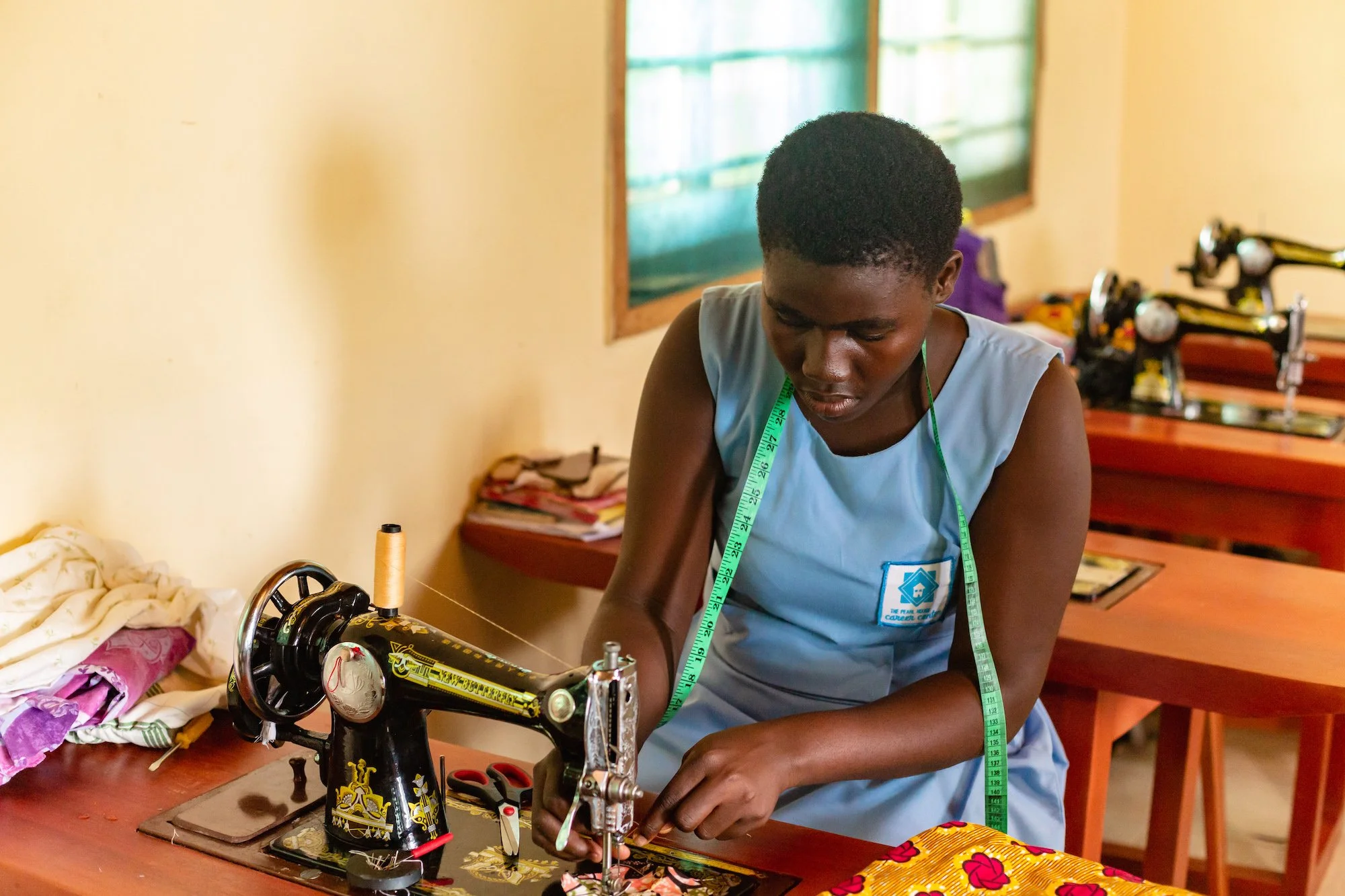 Young women learning sewing skills at the Pearl House Sewing Career Center