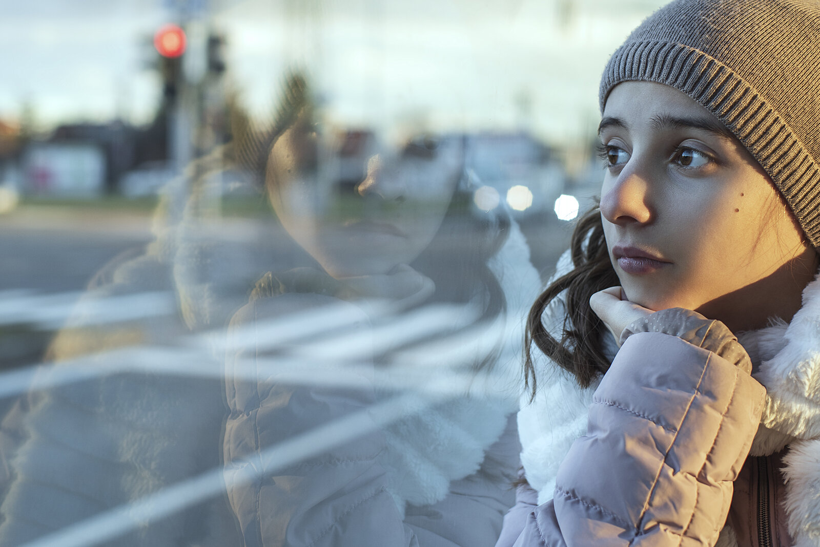 Teen girl looking sad out the window in New York. Talking about Health anxiety with children and teens during the COVID 19 pandemic of Coronavirus in New York, New York