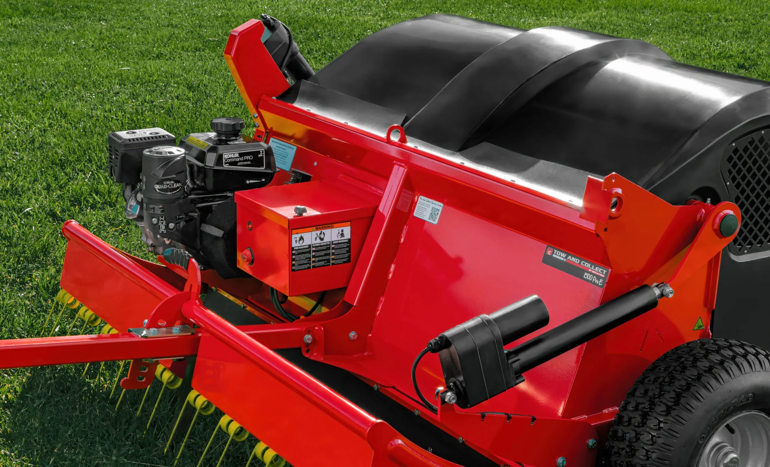 Close-up of a red lawn mower with a black engine and yellow blades, on a grassy field.