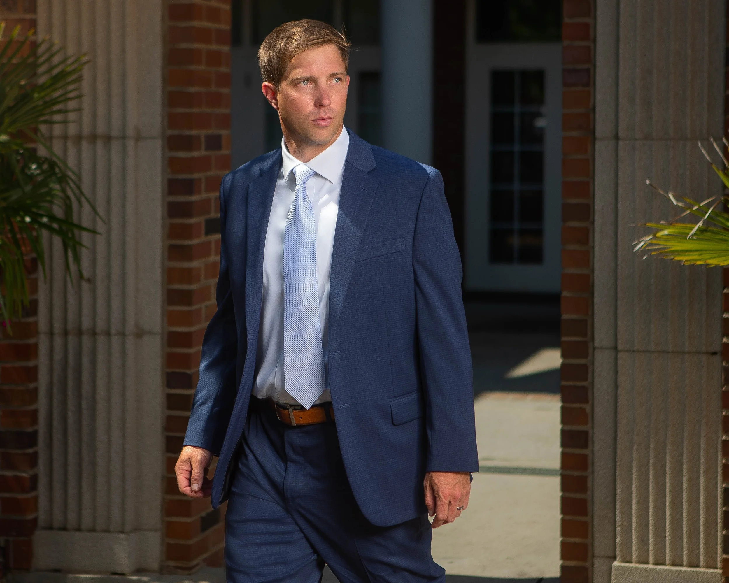 Attorney walking near brick columns in downtown Aiken, SC — professional brand photography by Weaver Media