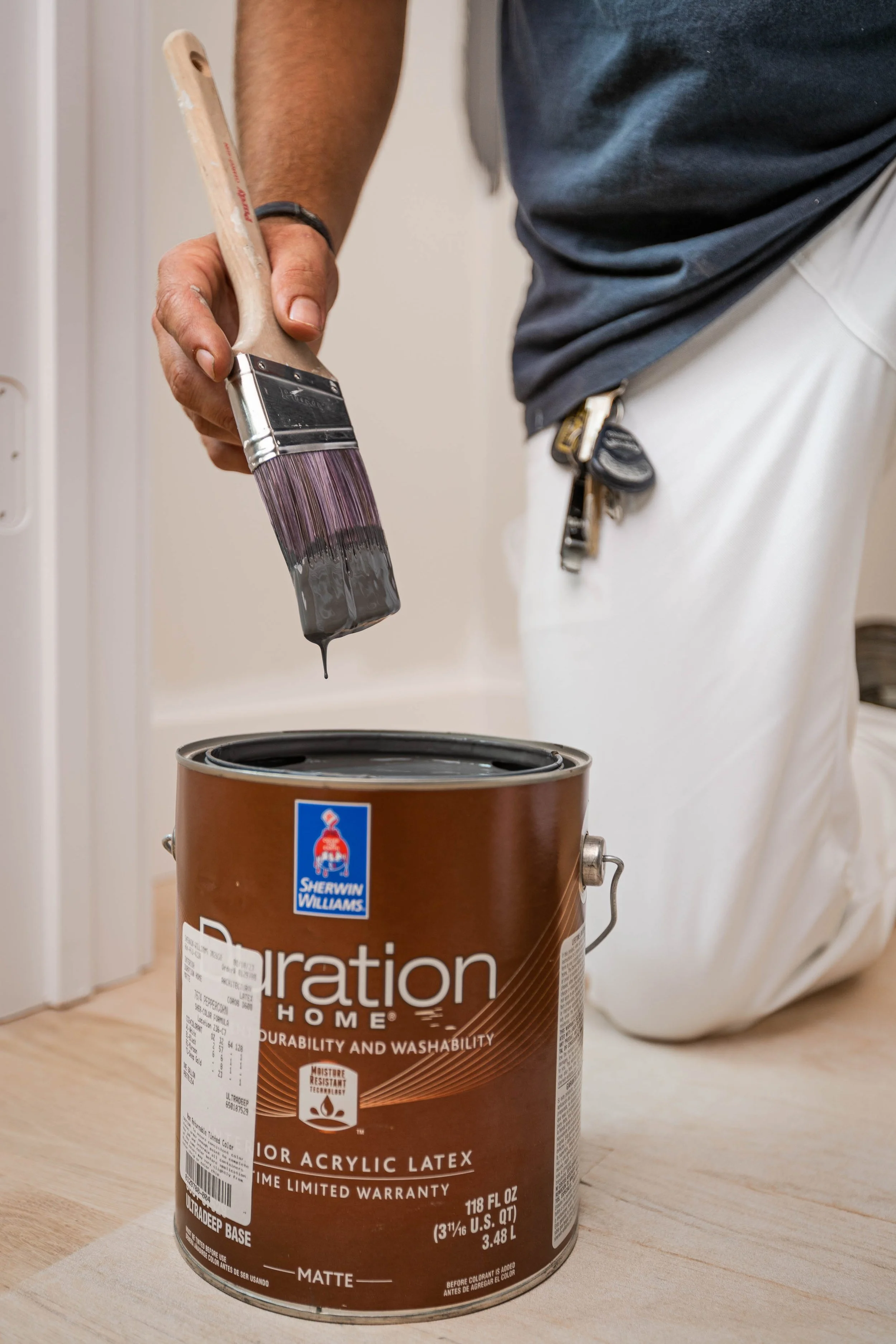 Painter dipping brush into Sherwin Williams Duration Home paint during Upstate Custom Coatings project in Greenville, SC — painting company photography
