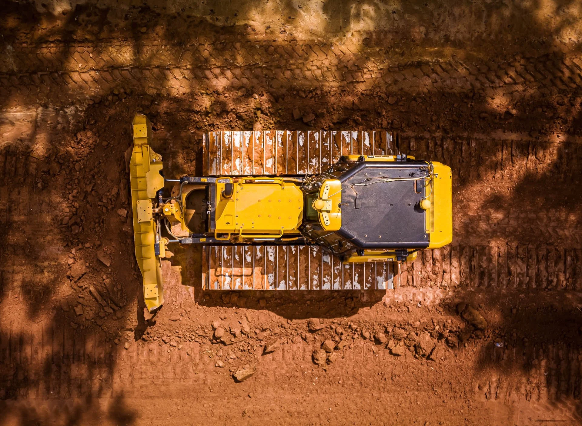 Top-down drone photograph of a Caterpillar bulldozer doing grading and site work on dirt, with tracks and blade near Greenville, SC.