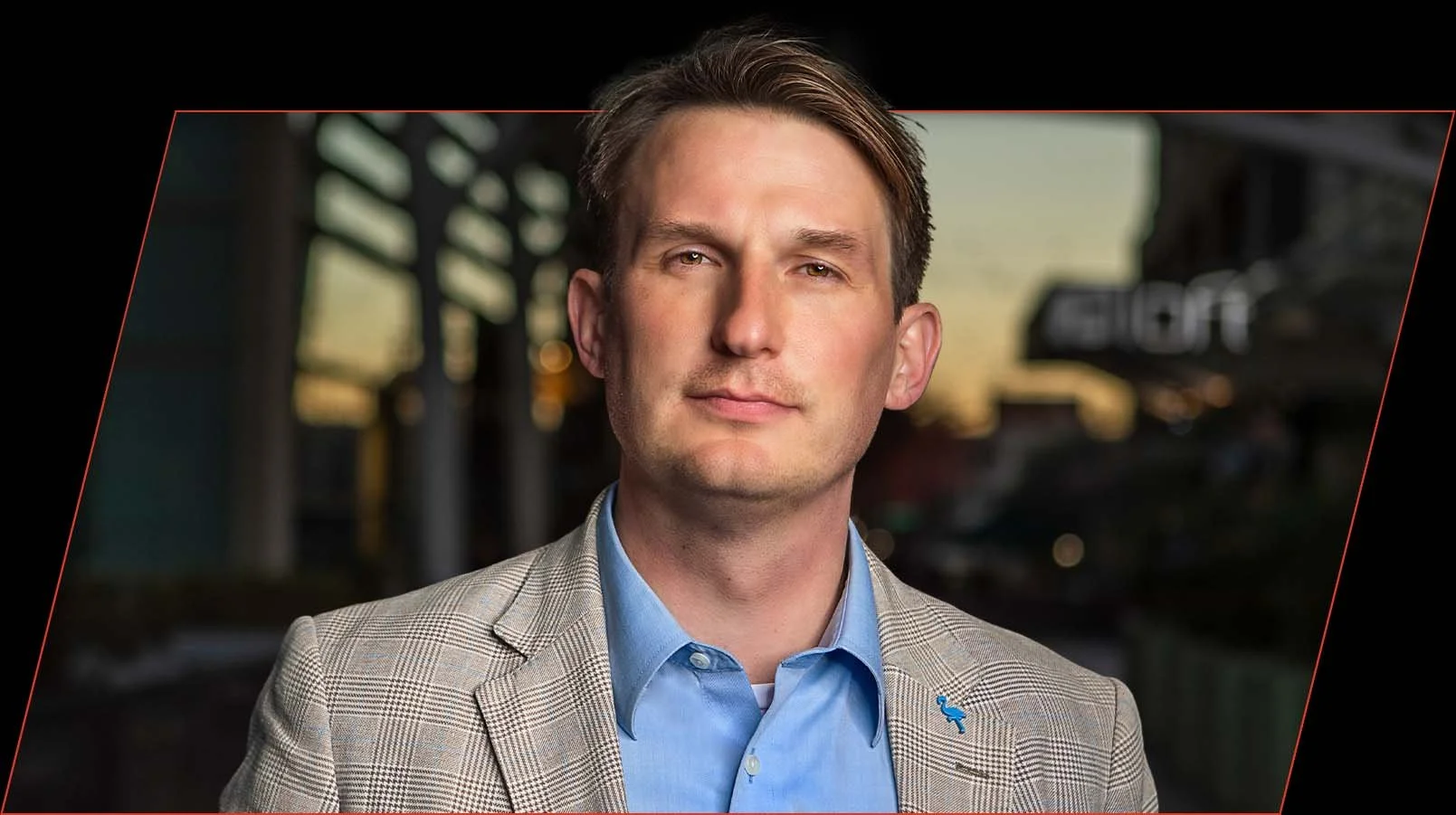 Testimonial portrait of Alex K at sunset with modern sun-lit buildings in the background