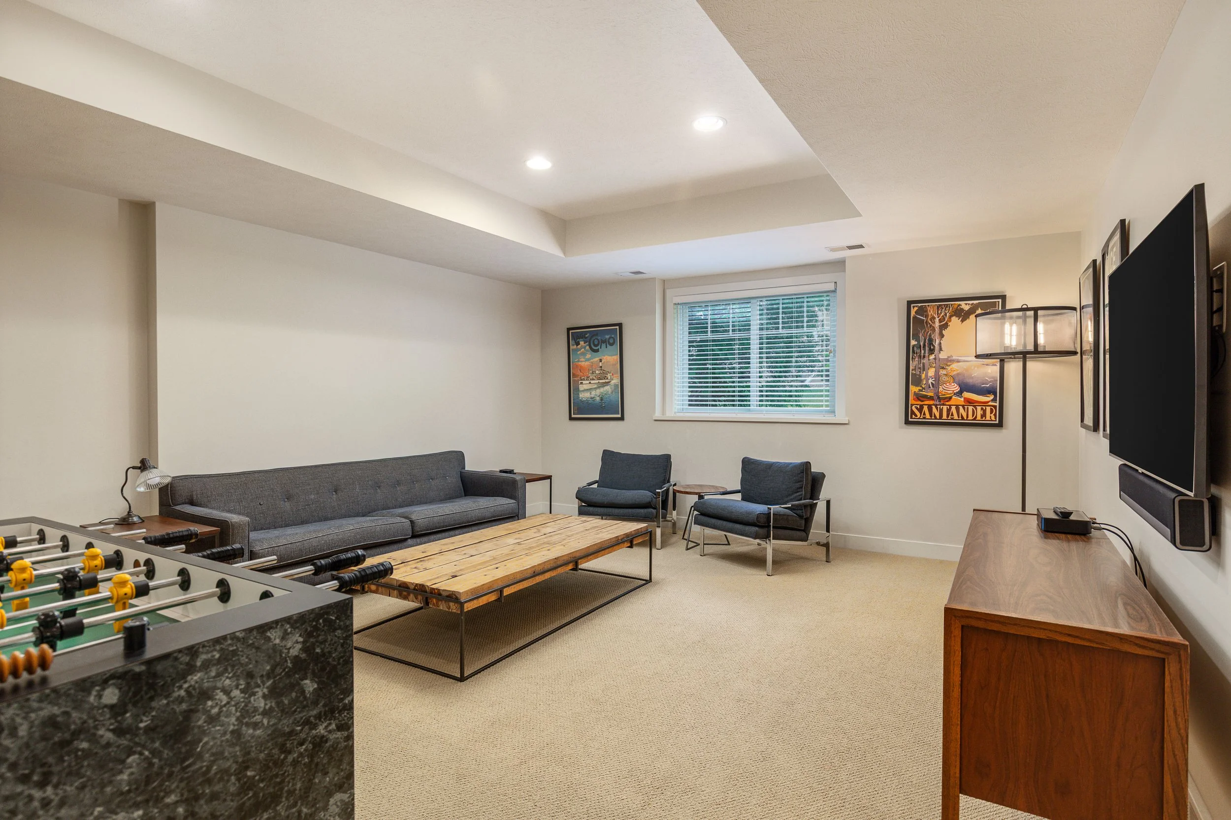 Living room downstairs is adjacent to the game room, with ping pong, foosball, and a TV