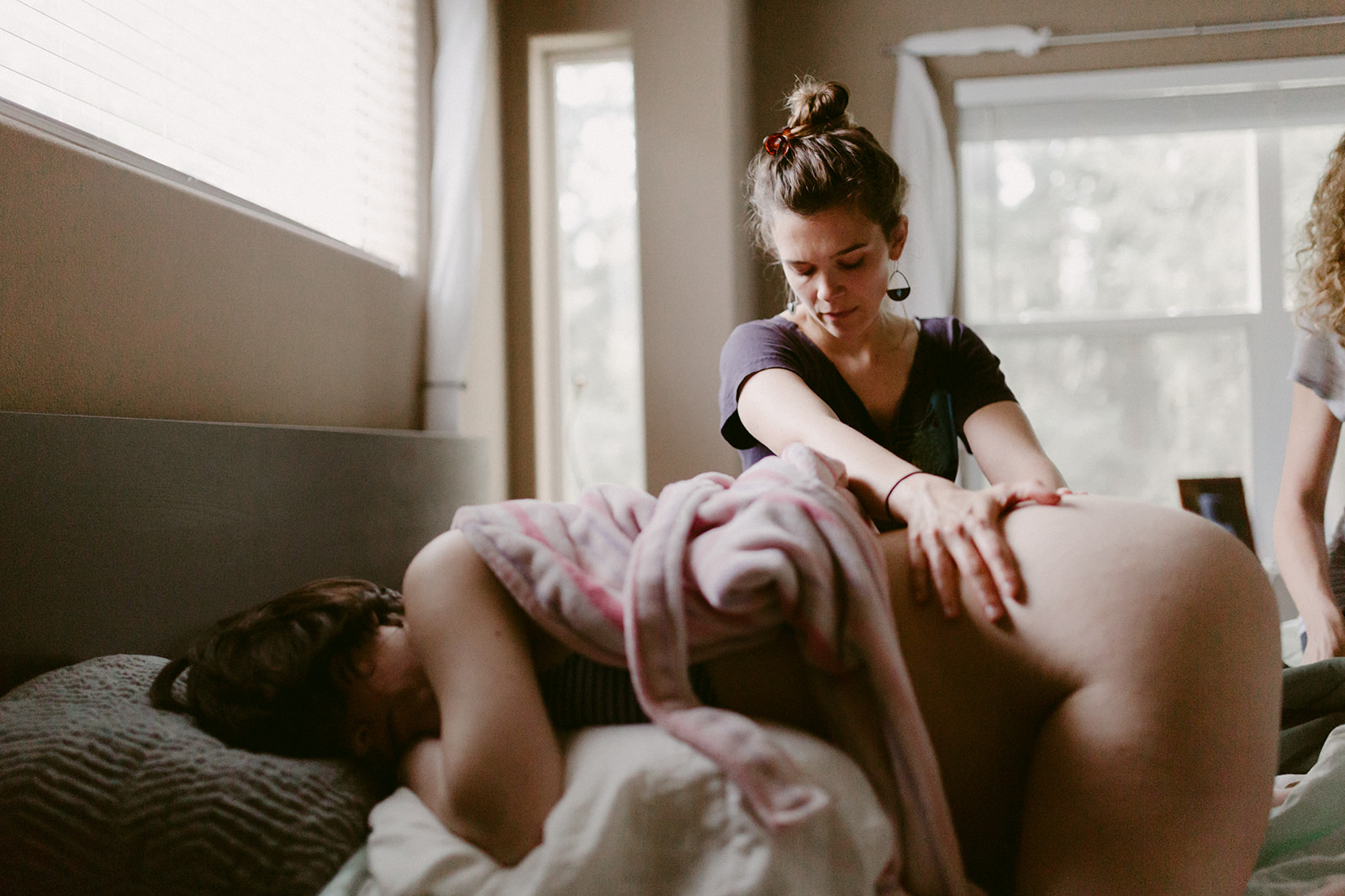 Midwife Lucy French applies pressure and massage during a home birth.