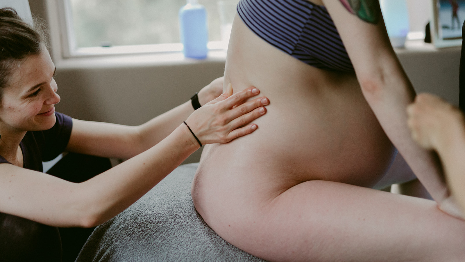 Midwife Lucy French massages her patient's back during a home birth.