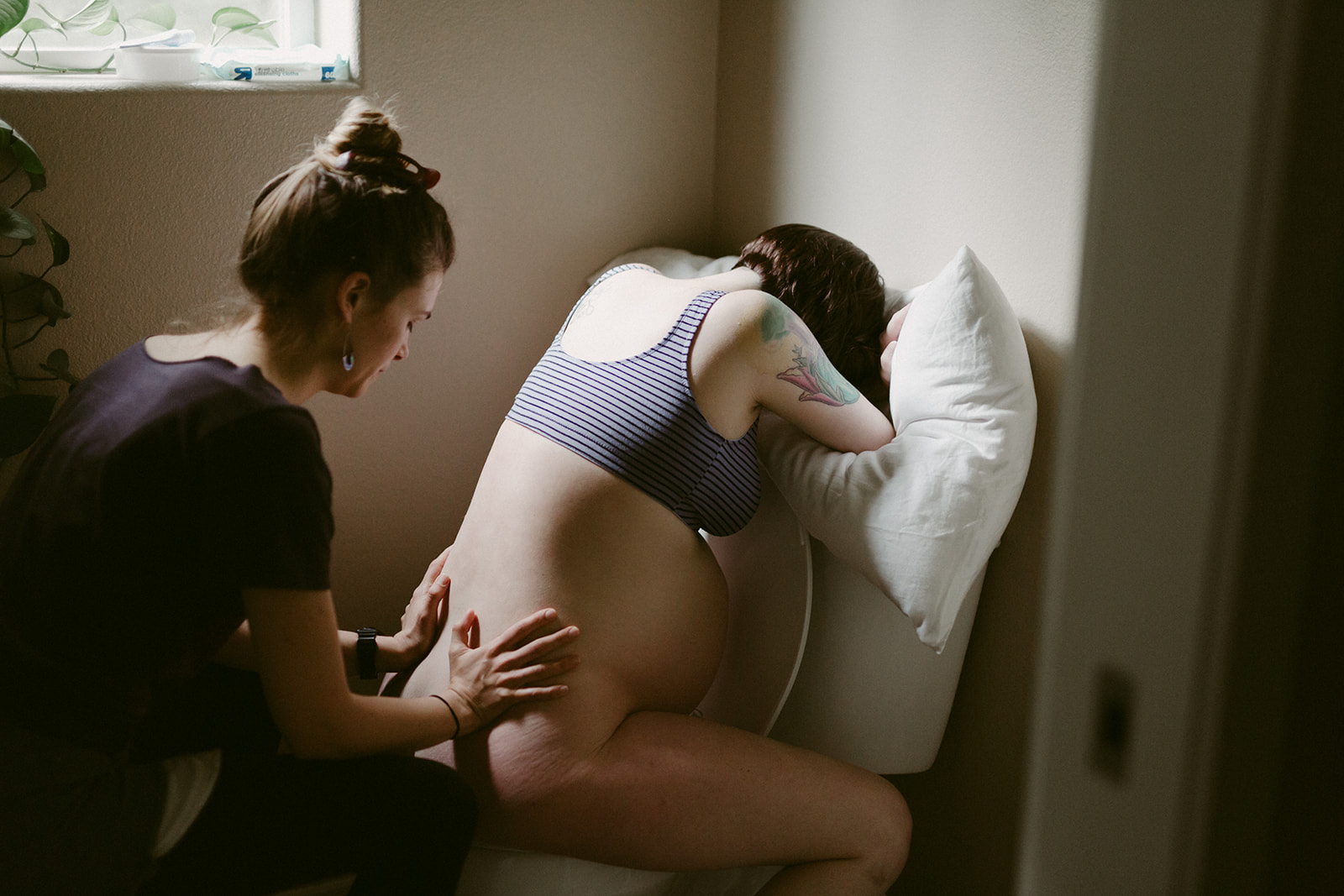 Midwife Lucy French massages her patient's back during a home birth.