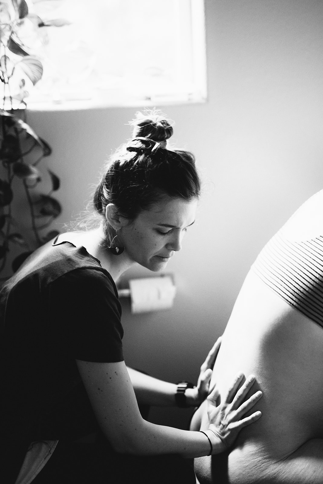 Midwife Lucy French applies pressure to the patient's back during a home birth.