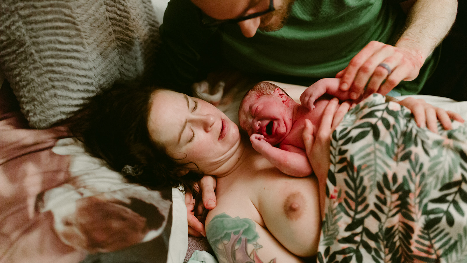 A newborn baby cries on the mother's chest immediately after home birth.