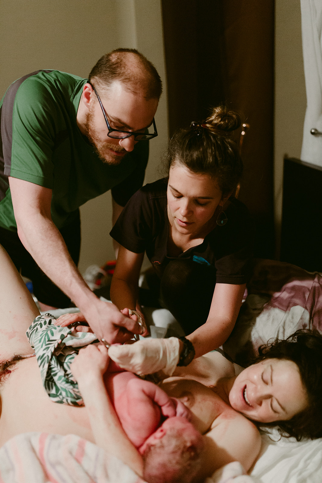Midwife Lucy French assists a father to cut his newborn baby's umbilical cord at a home birth.