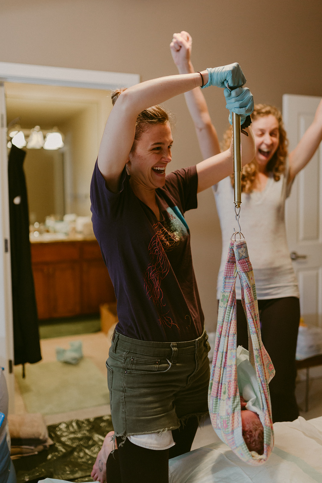 Midwives cheer upon weighing a healthy newborn baby at a home birth.