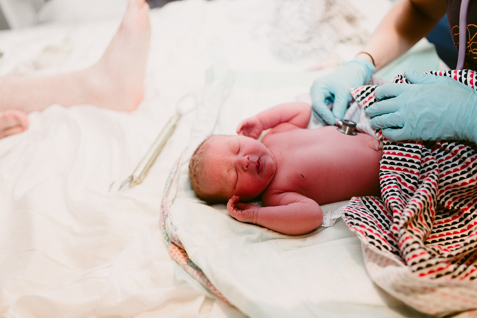 Midwife Lucy French places a stethoscope on the abdomen of a sleeping newborn. 