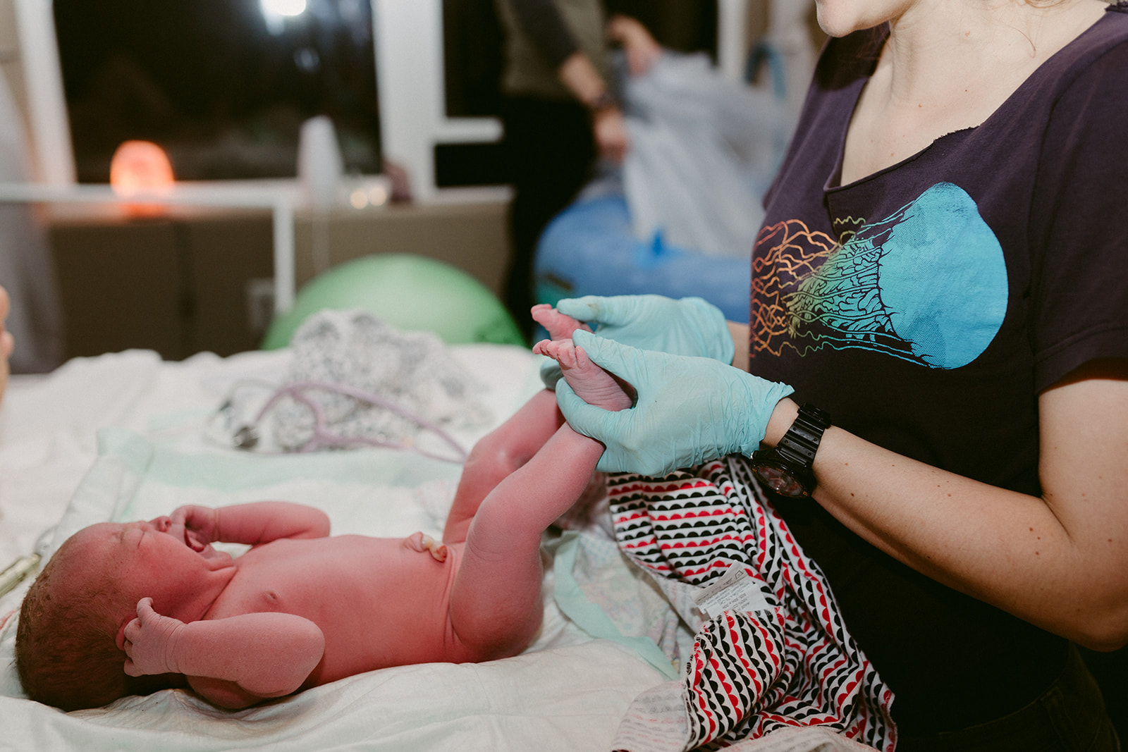 Midwife Lucy French inspects the legs of a newborn at a home birth.