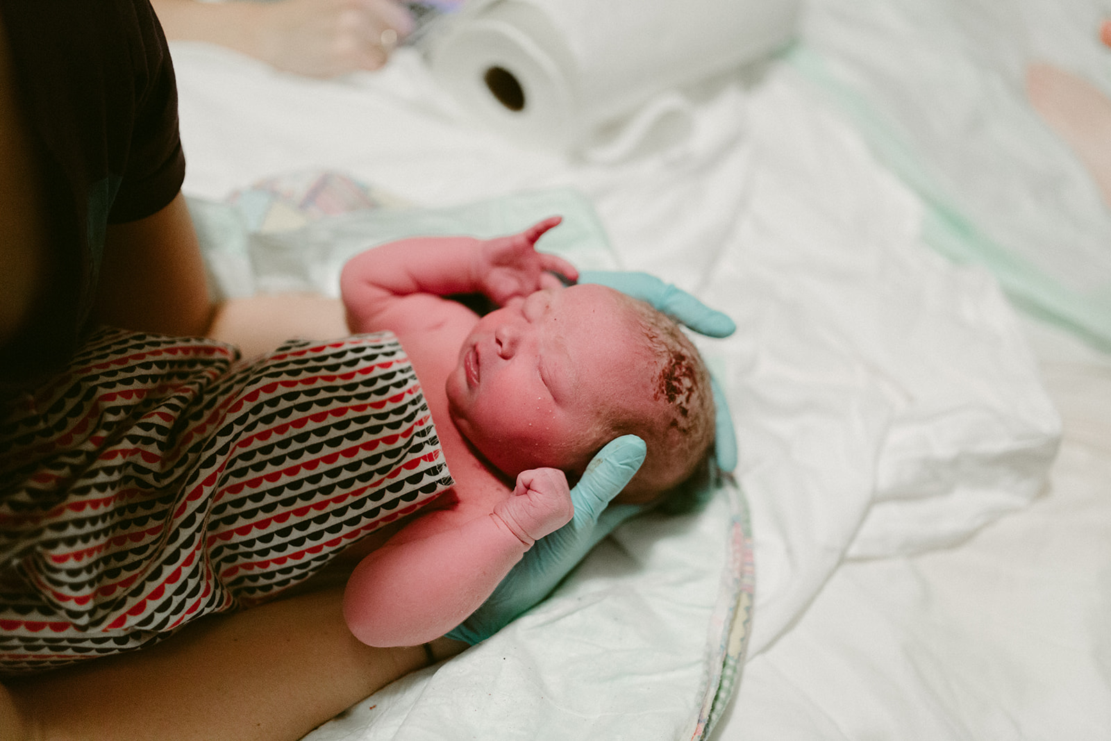 Midwife Lucy French holds the newborn baby at a home birth.