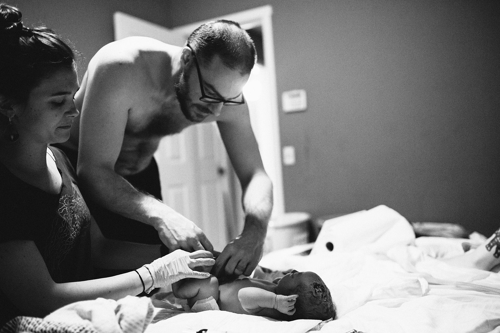 Midwife Lucy French assists a new father to diaper his child at a home birth.