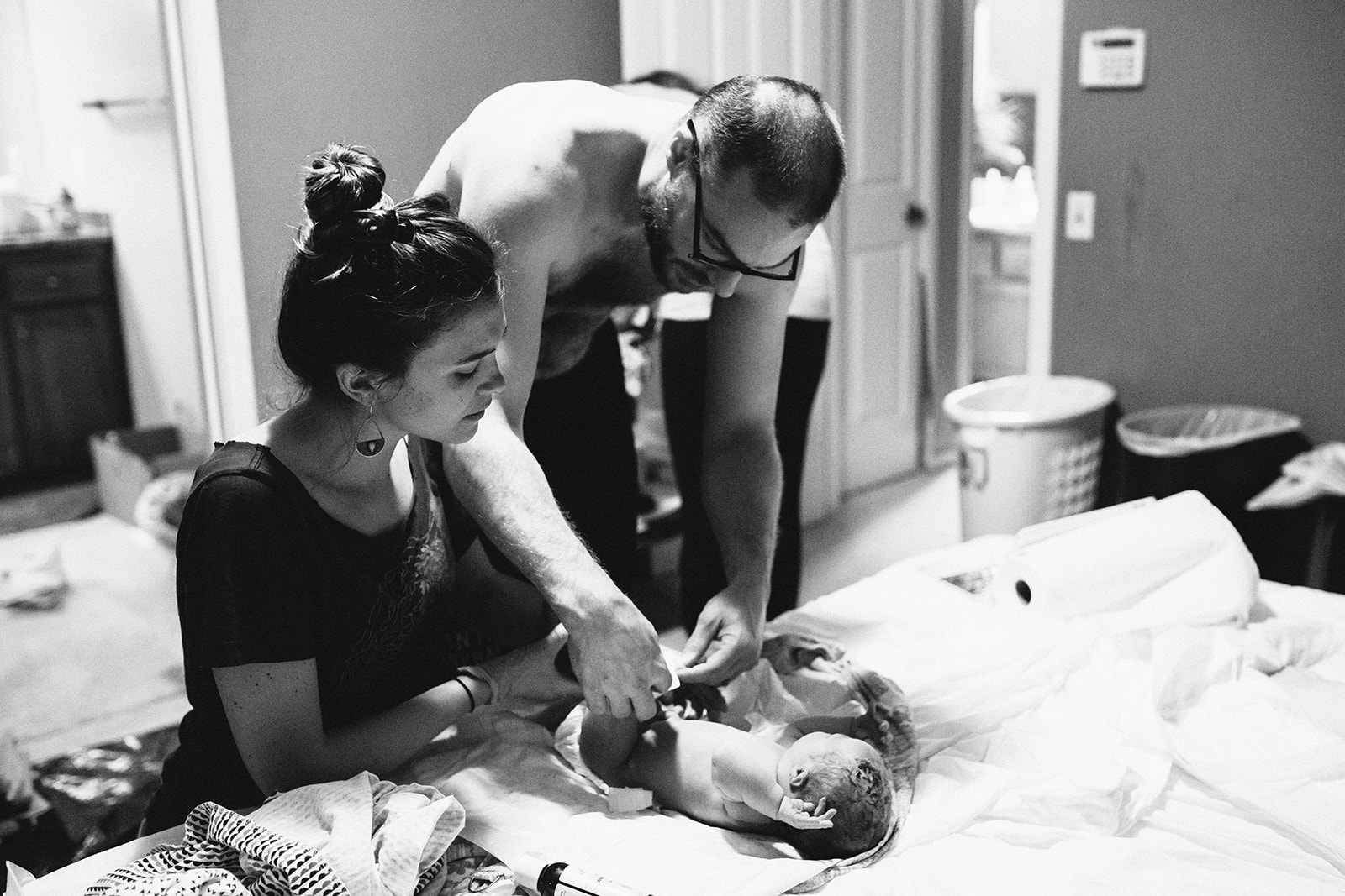 Midwife Lucy French assists a new father to diaper his child at a home birth.