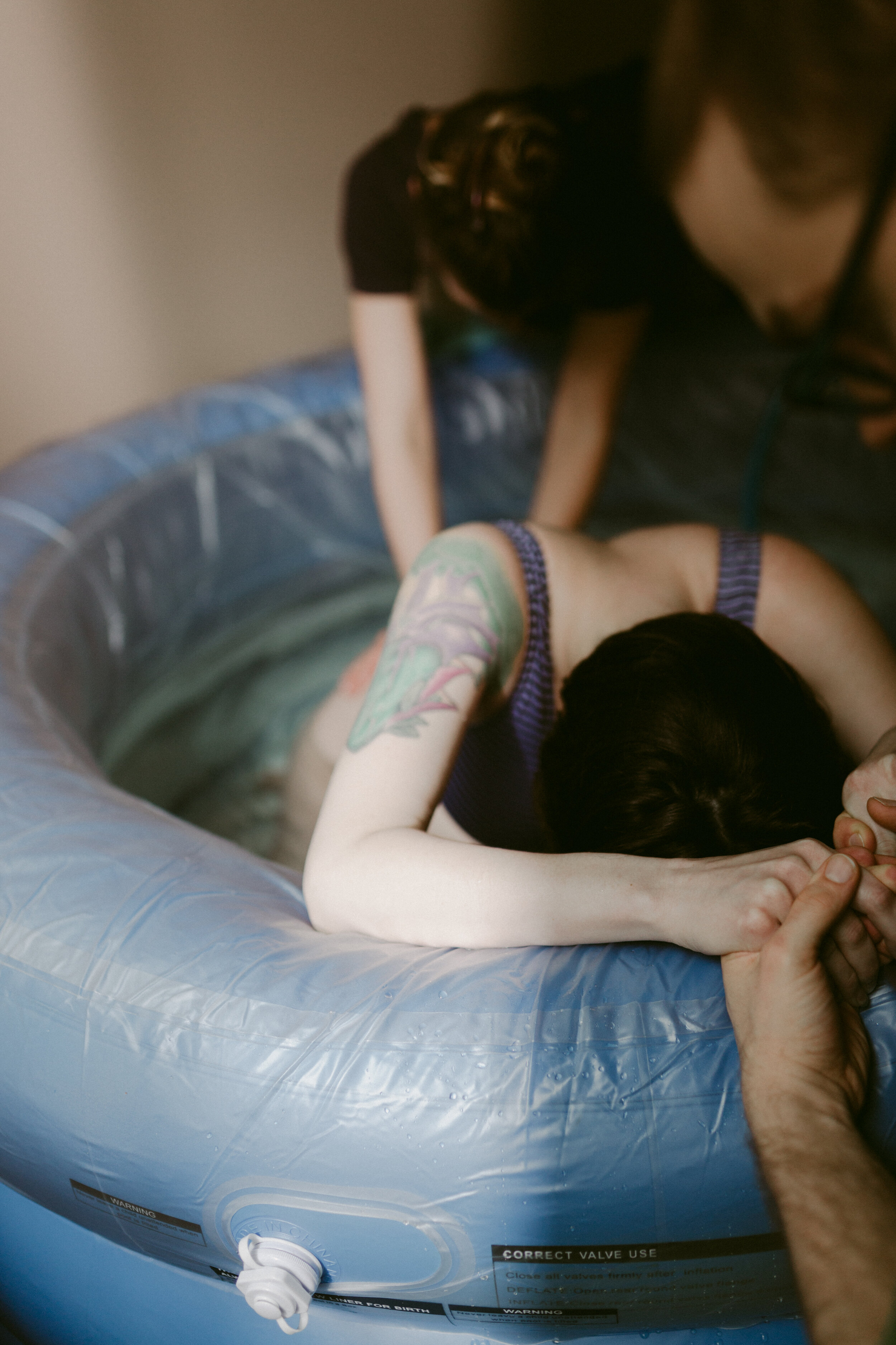 Midwife Lucy French applies pressure to a laboring mother's lower back during a water birth.