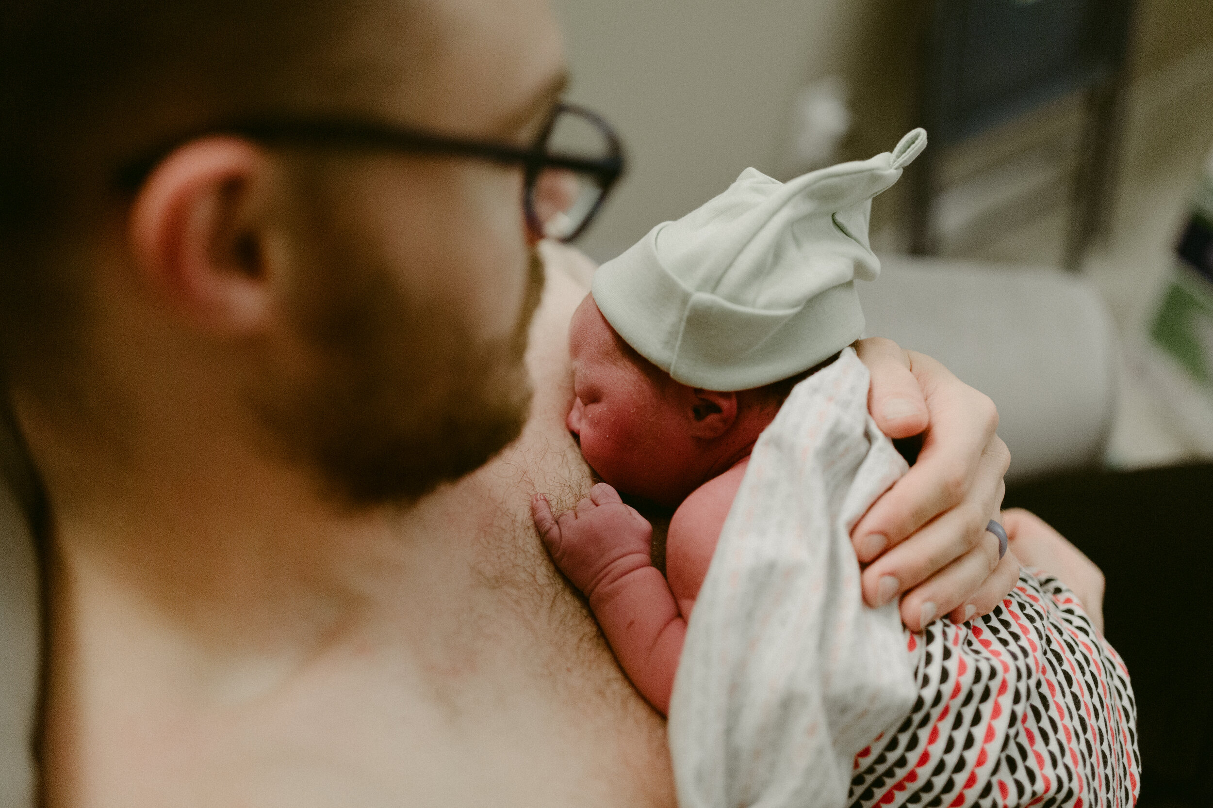 A father holds his newborn baby against his chest at a home birth.