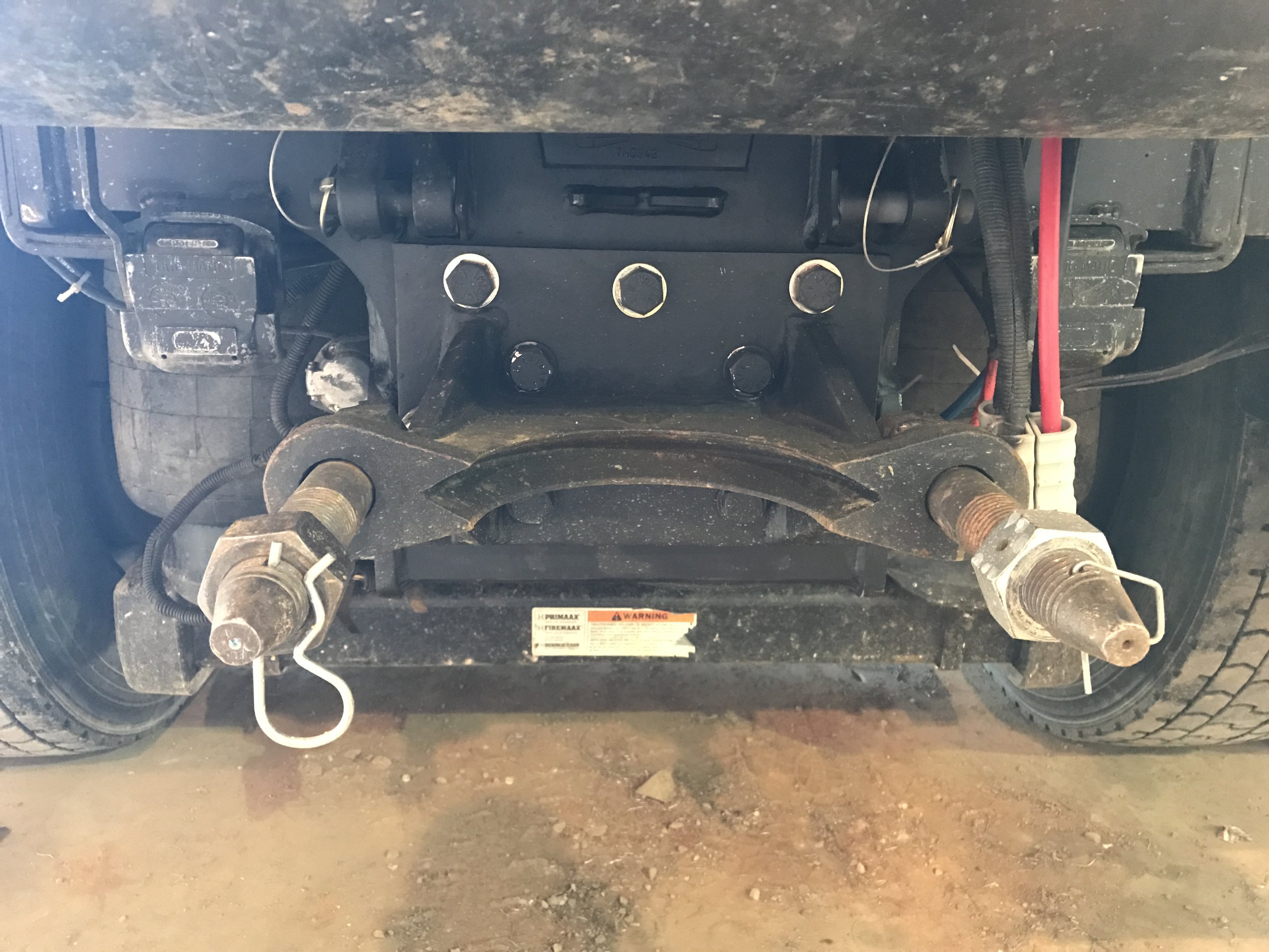 Underneath of a vehicle showing drawbar ARD62, including two rusty bolts, a black metal frame, a red cable, and a plastic connector.
